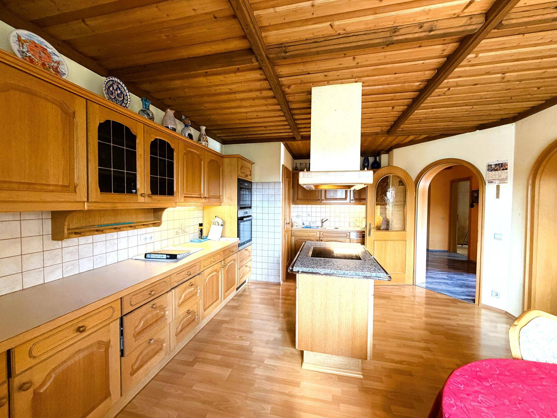 Traditionelle Holzküche mit Kücheninsel, Granitarbeitsplatte und rustikaler Holzdecke.