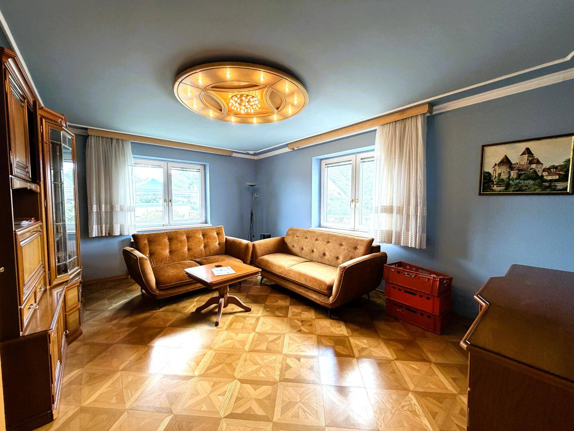 Wohnzimmer mit gemustertem Parkettboden, blauen Wänden und zwei bequemen Sofas.