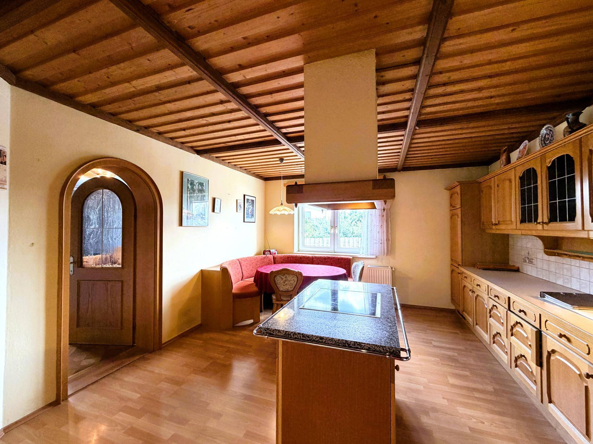 Gemütliche Holzküche mit Eckbank-Essbereich, Kücheninsel und rustikaler Holzdecke.
