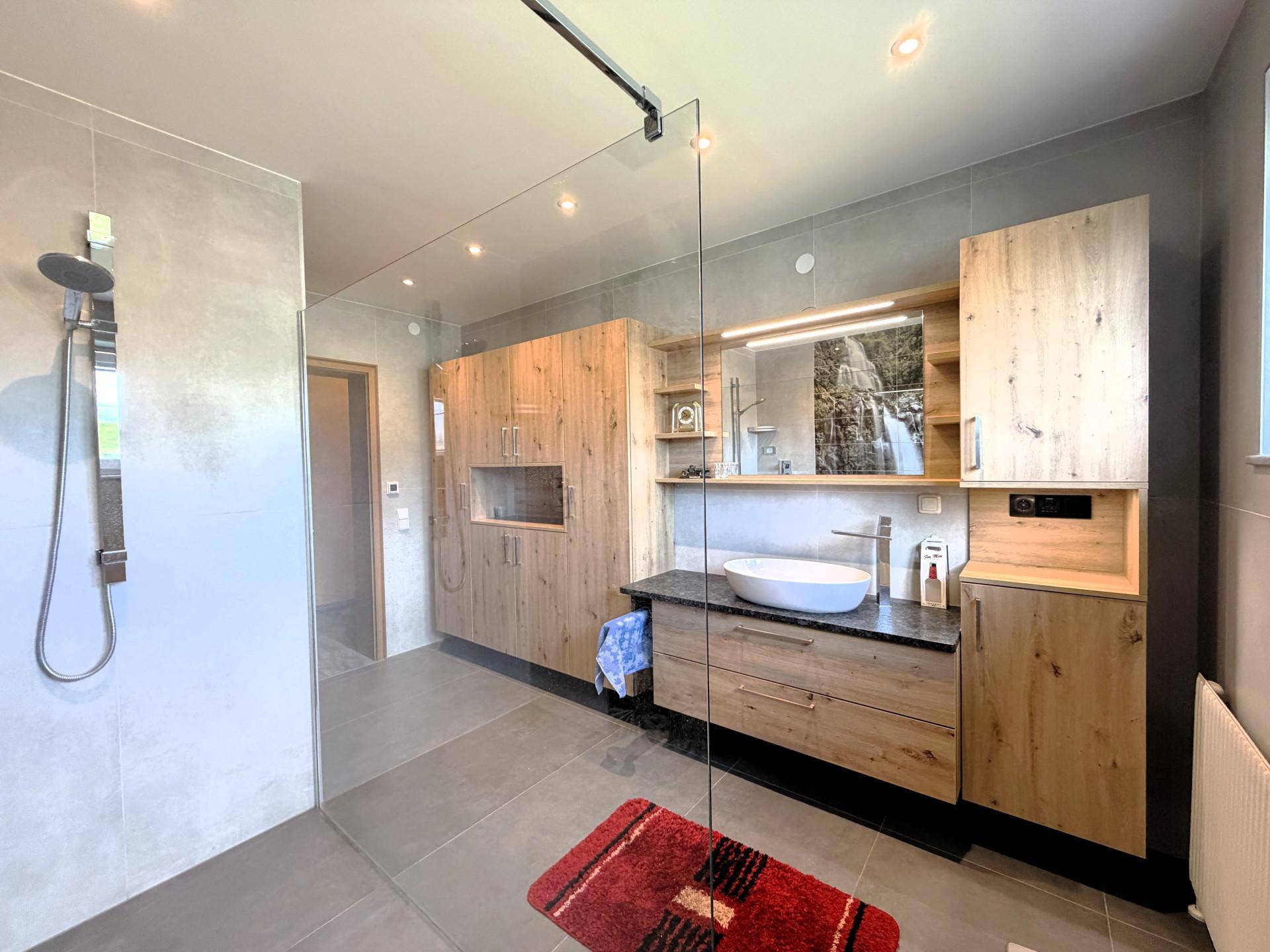 Zeitgemäßes Badezimmer mit begehbarer Dusche, elegantem Waschbecken und Holzmöbeln.