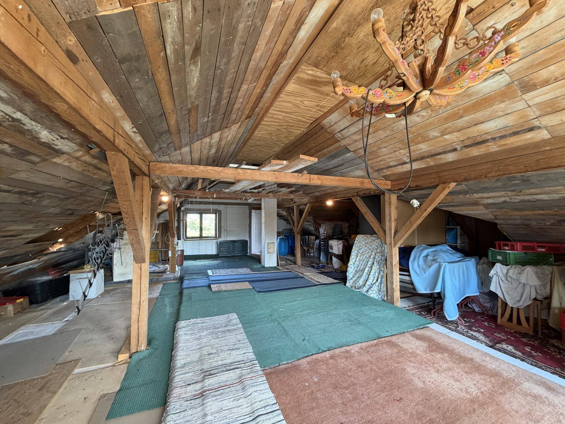 Geräumiger Dachboden mit sichtbaren Holzbalken und Holzverkleidung, bietet viel Stauraum.