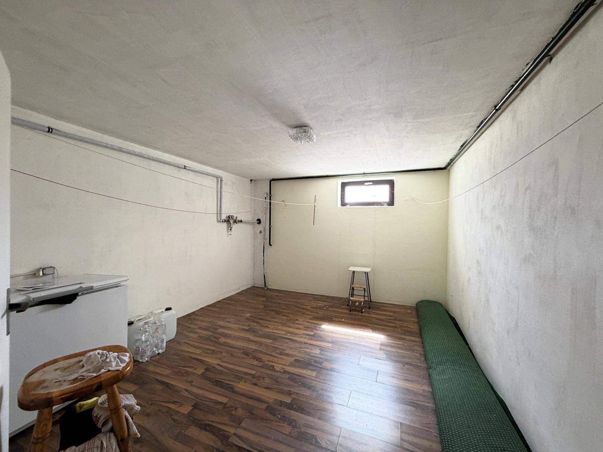 Kellerraum mit Laminatboden, kleinem Fenster und einfacher Ausstattung.