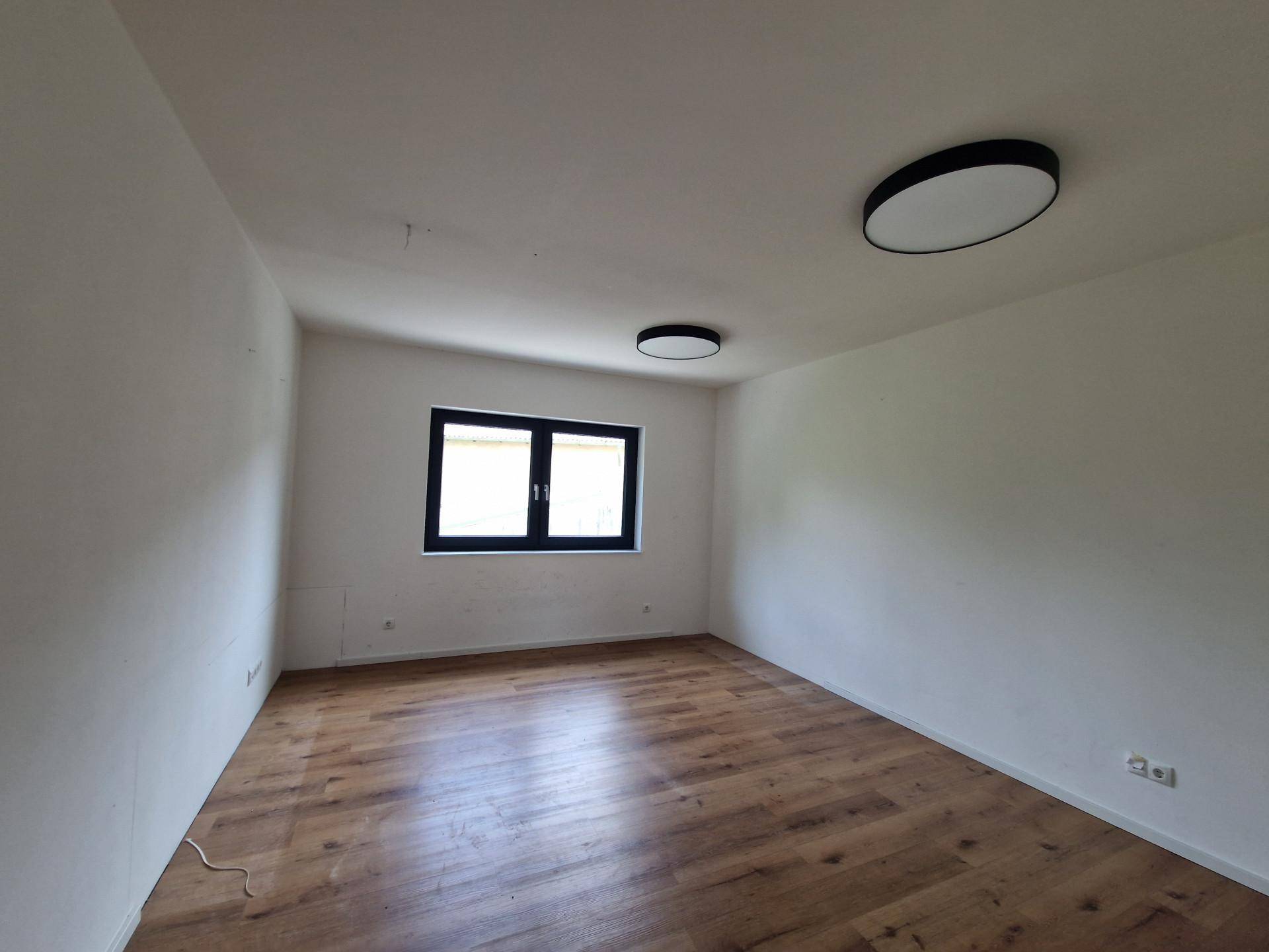 Schlichter, heller Raum mit Holzboden und einem Fenster, ideal für verschiedene Nutzungsmöglichkeiten.