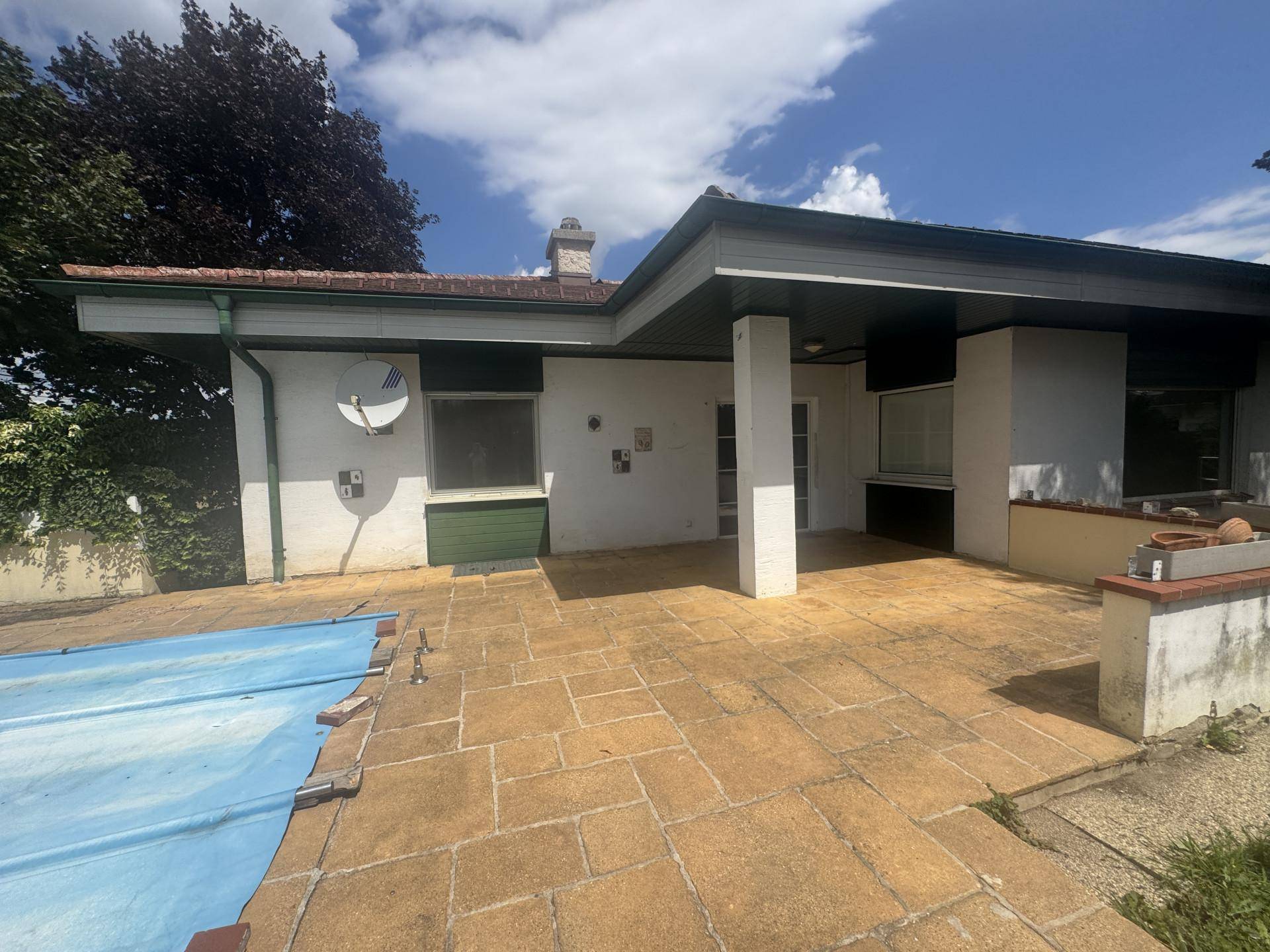 Große gepflasterte Terrasse neben dem überdachten Poolbereich, ideal für Entspannung im Freien.