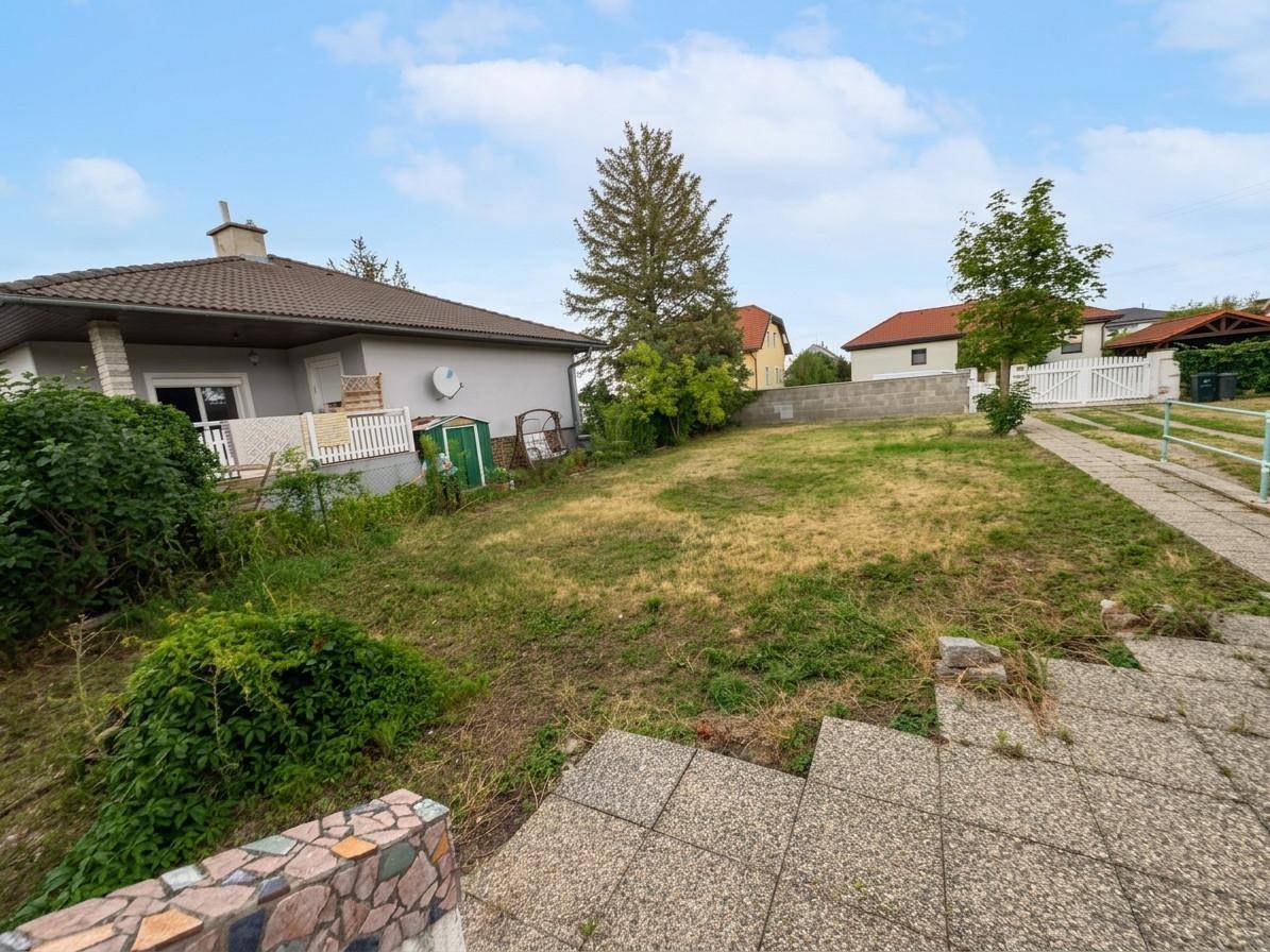 Außenansicht des Hauses mit großem Gartenbereich und gepflasterter Auffahrt unter blauem Himmel.