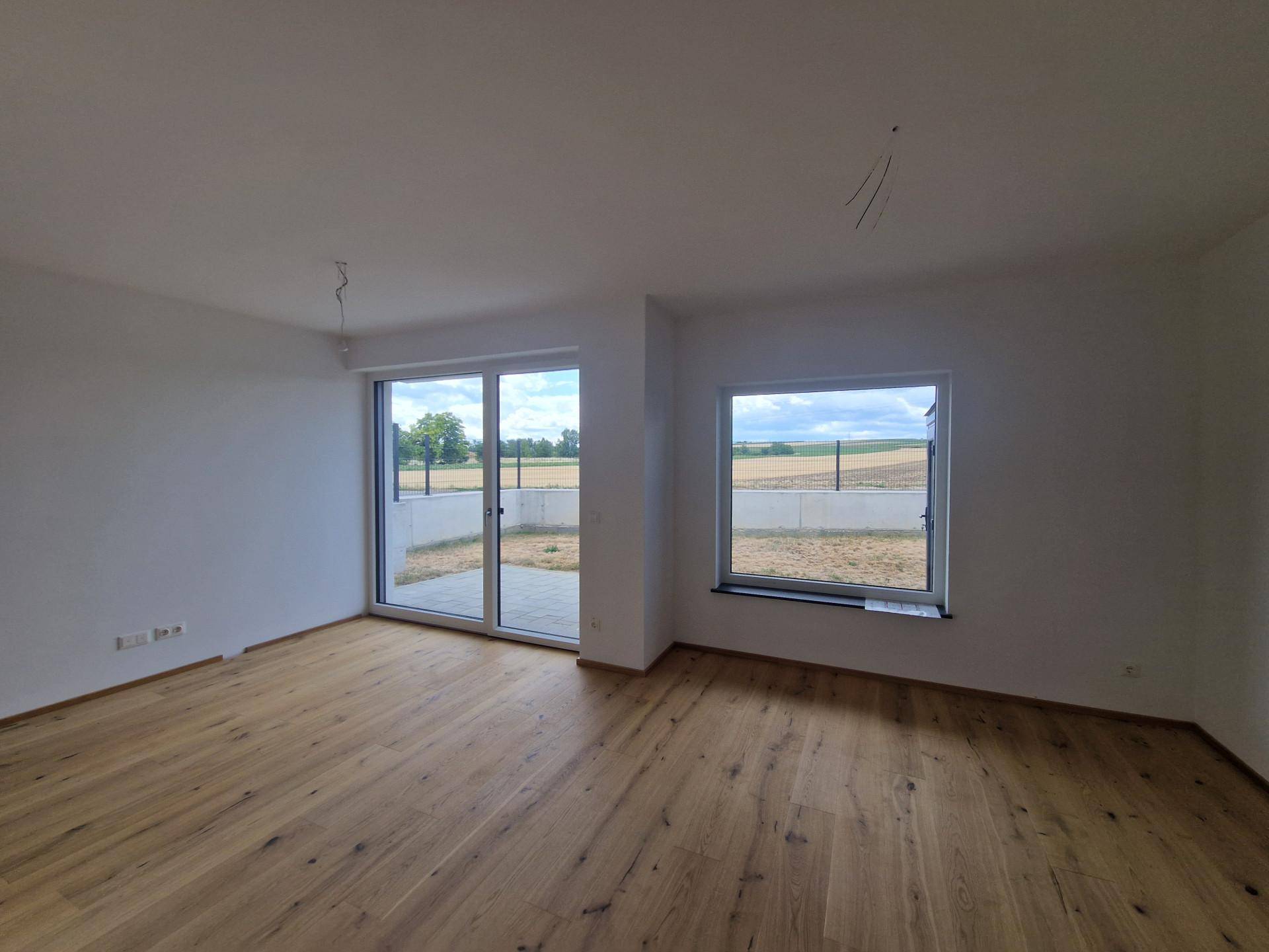 Heller Raum mit großen Schiebetüren zum Außenbereich und weitem Blick über die Felder.