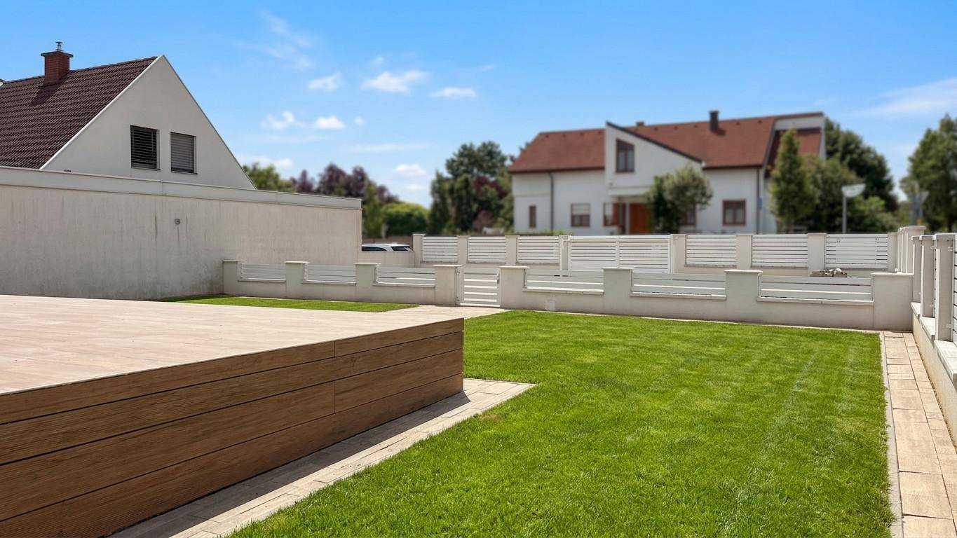 Gepflegter Gartenbereich mit großer Holzterrasse und weitläufiger Rasenfläche.