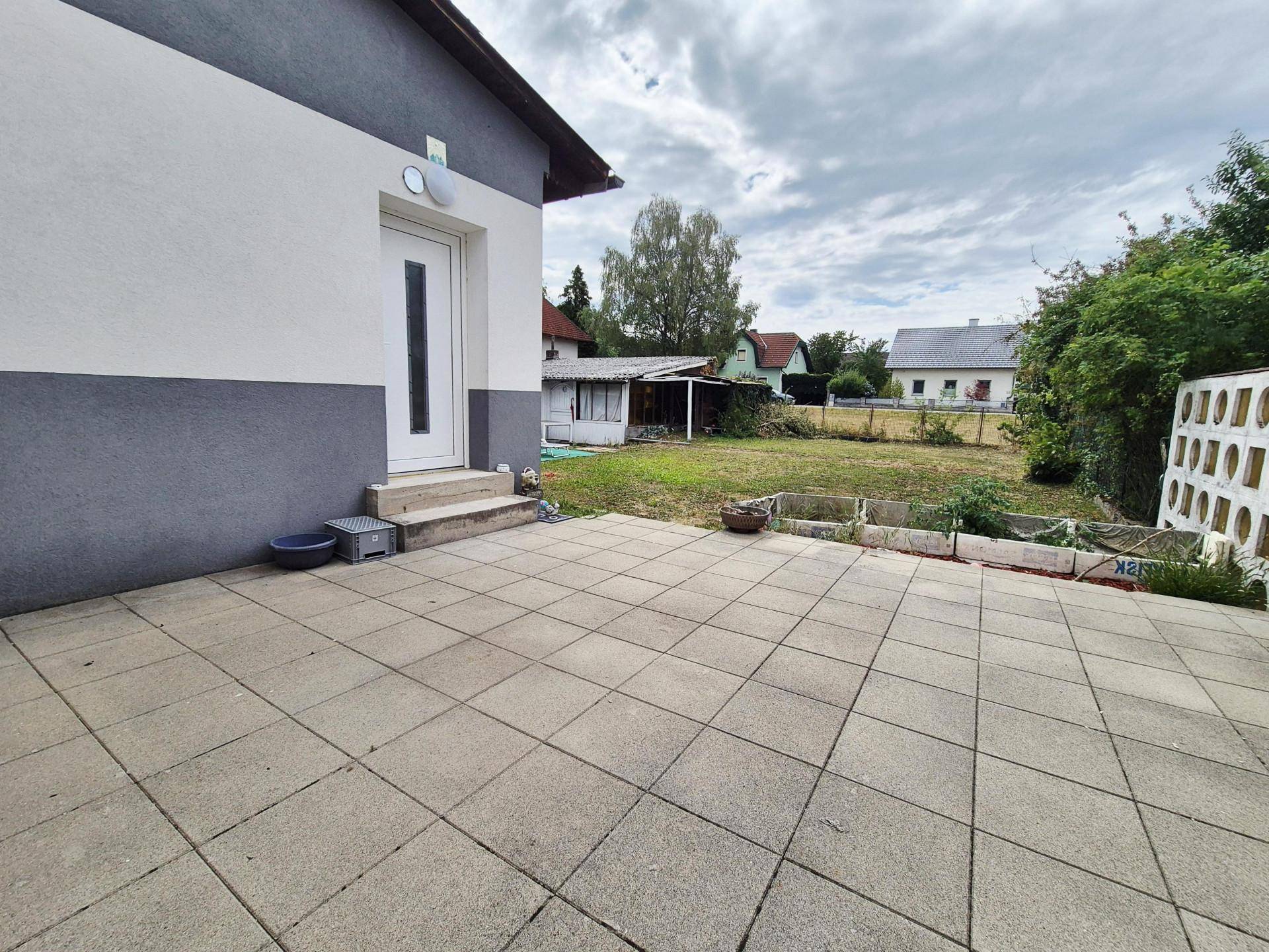 Geräumige gepflasterte Terrasse hinter dem Haus mit Blick auf den Garten.