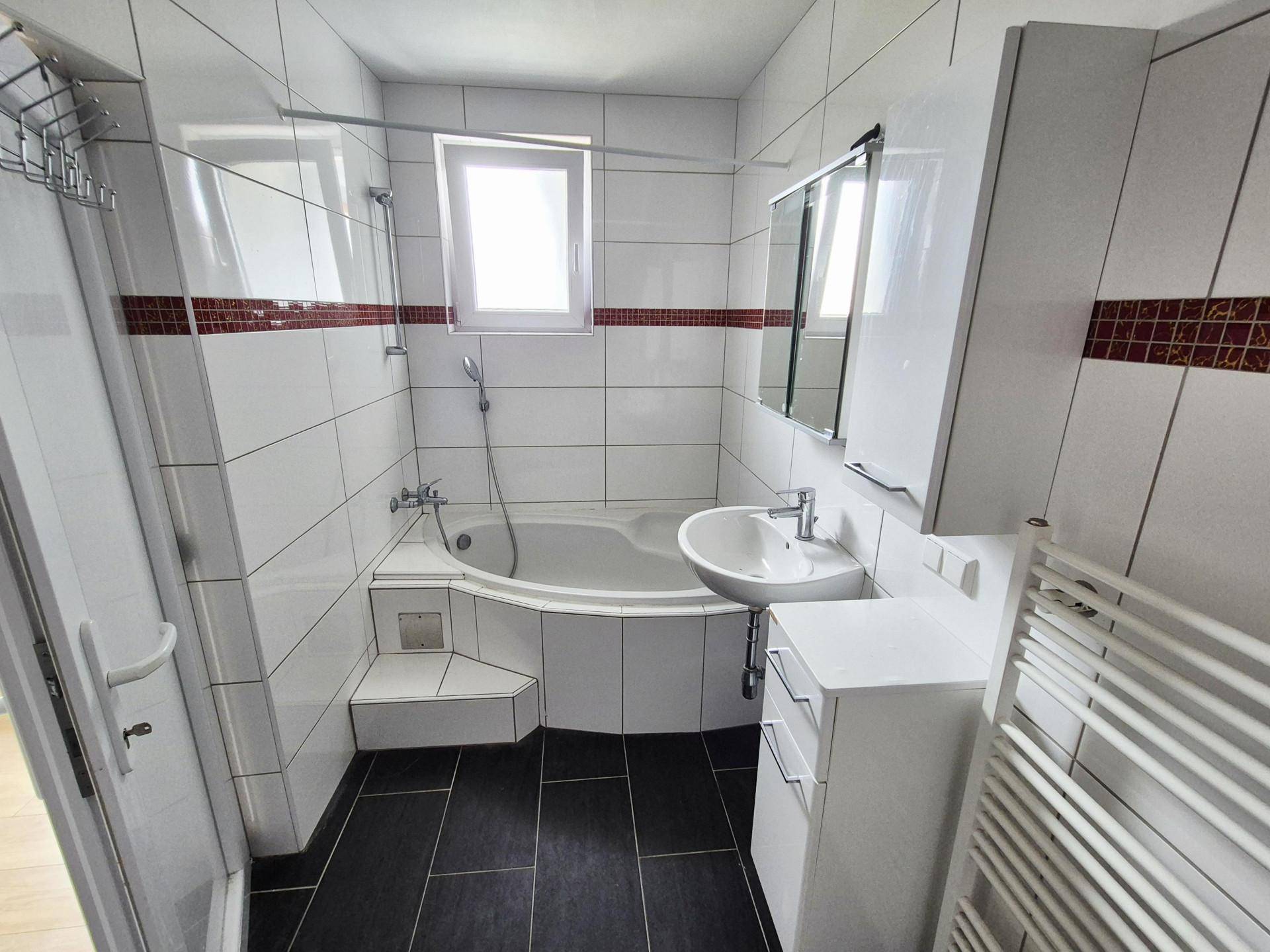 Komplettes Badezimmer mit Eckbadewanne, Dusche und Fenster für Tageslicht.