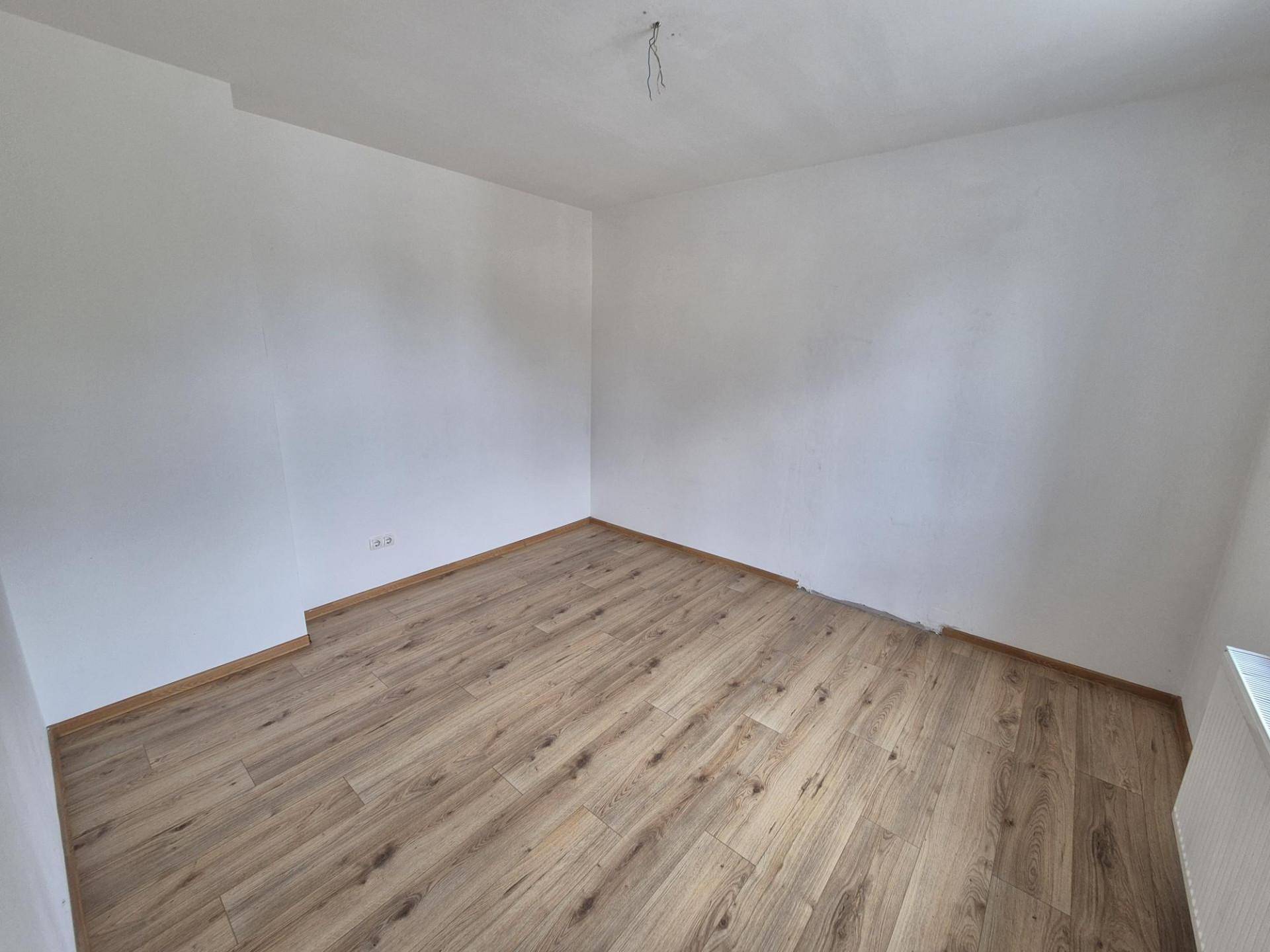 Leerer Raum mit hellem Laminatboden und weißen Wänden, bereit zur Einrichtung.