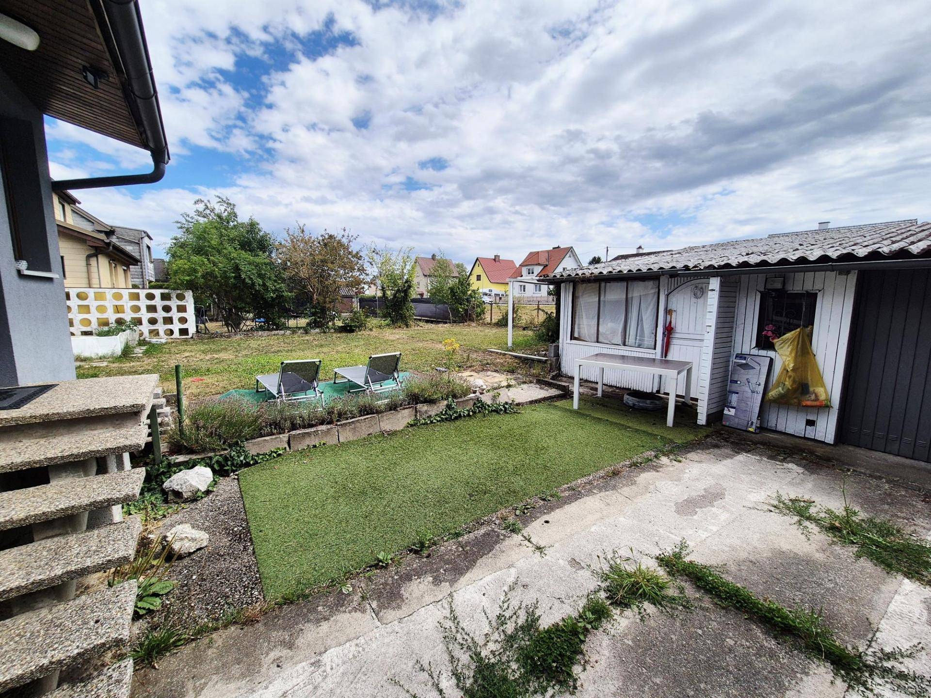 Großer Gartenbereich mit Rasenfläche, Gartenhaus und Liegestühlen.