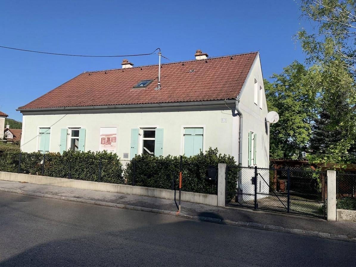 Vorderansicht des gepflegten Hauses mit hellen Fensterläden und einem kleinen Vorgarten.