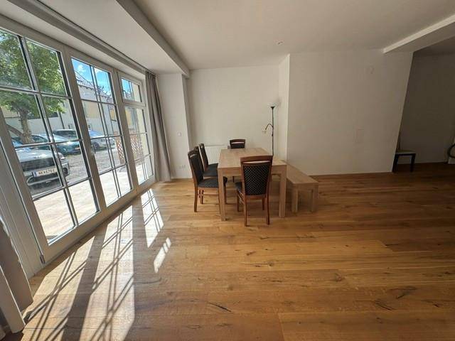 Essbereich mit Holztisch und Stühlen, direkt an großen Fenstern mit viel Tageslicht.