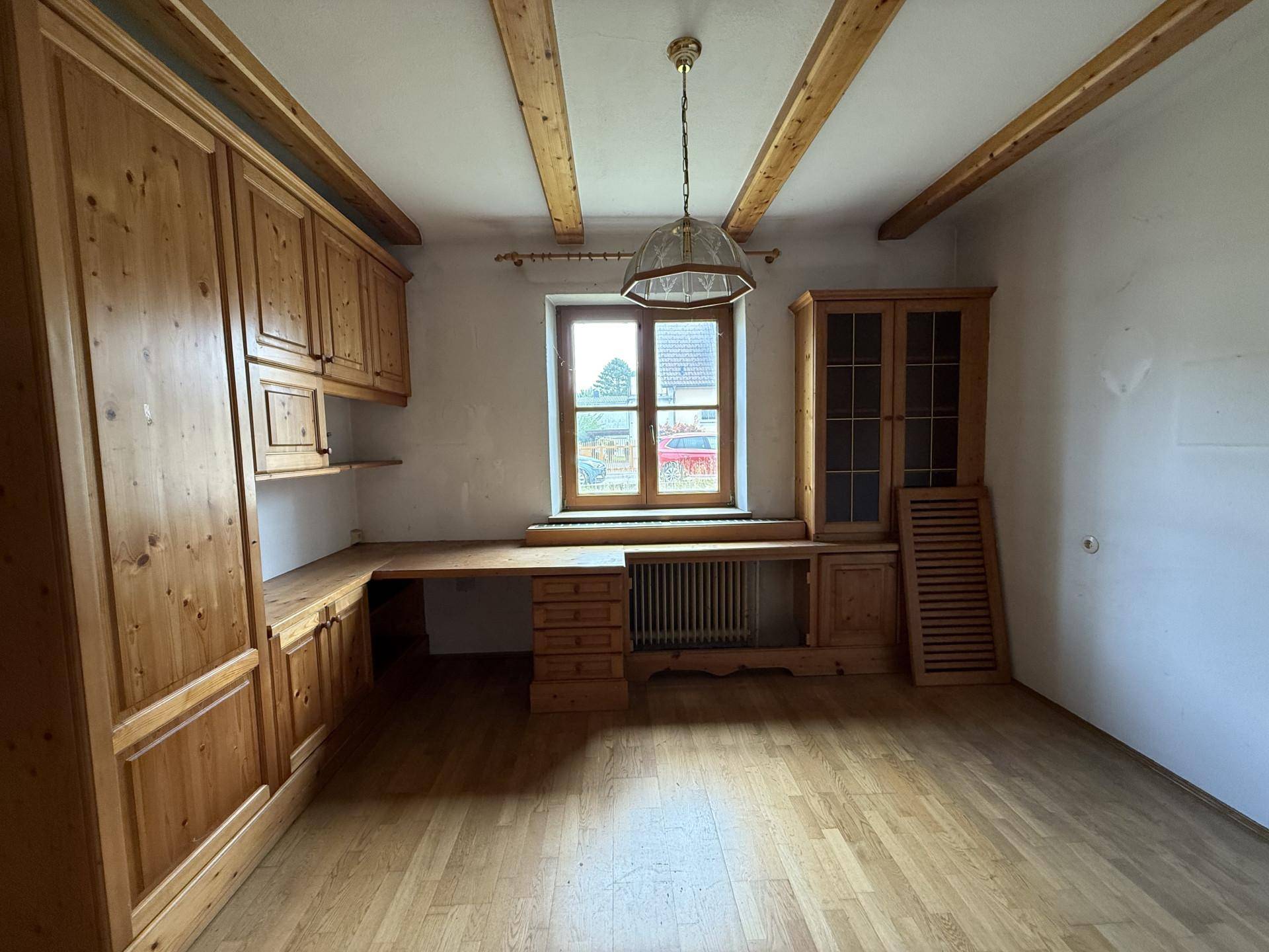 Ein Raum mit umfangreichen Einbaumöbeln aus Holz, einem Schreibtisch und sichtbaren Deckenbalken.