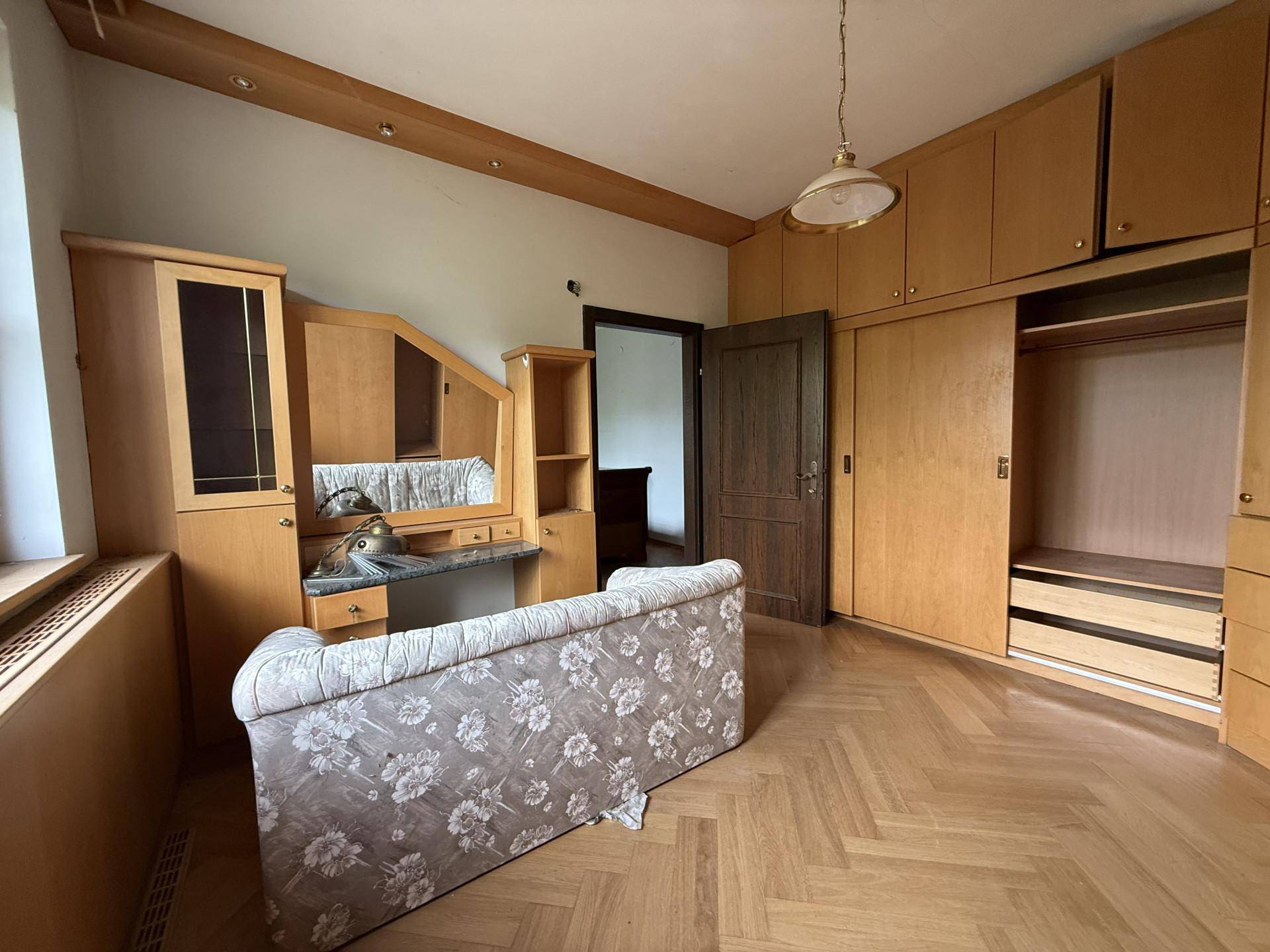 Ein Schlafzimmer mit Einbauschränken, einem Schminktisch und einem Sofa auf Fischgrätparkett.