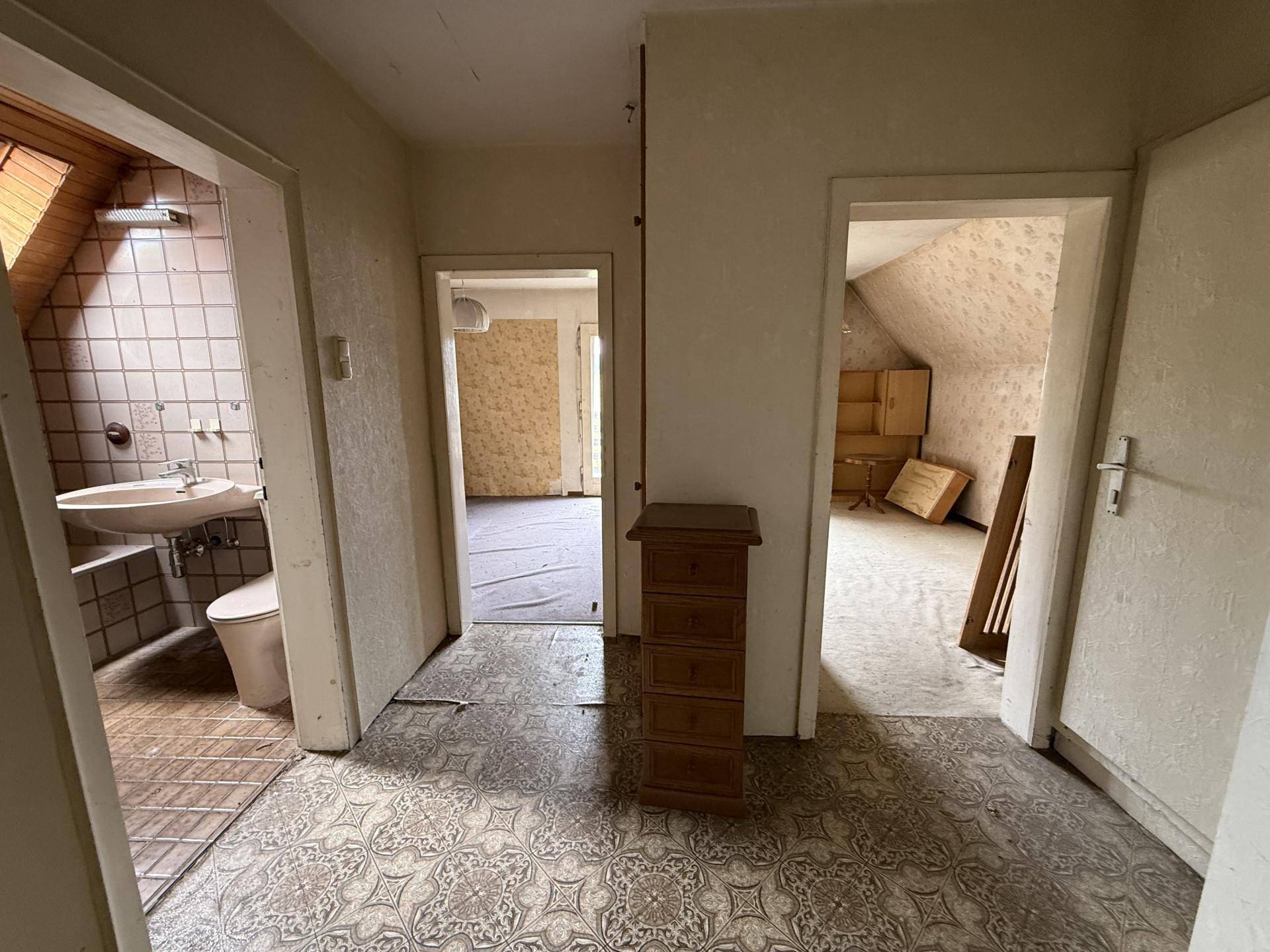 Ein Flur im Dachgeschoss mit Zugang zu einem Badezimmer und weiteren Räumen unter der Dachschräge.