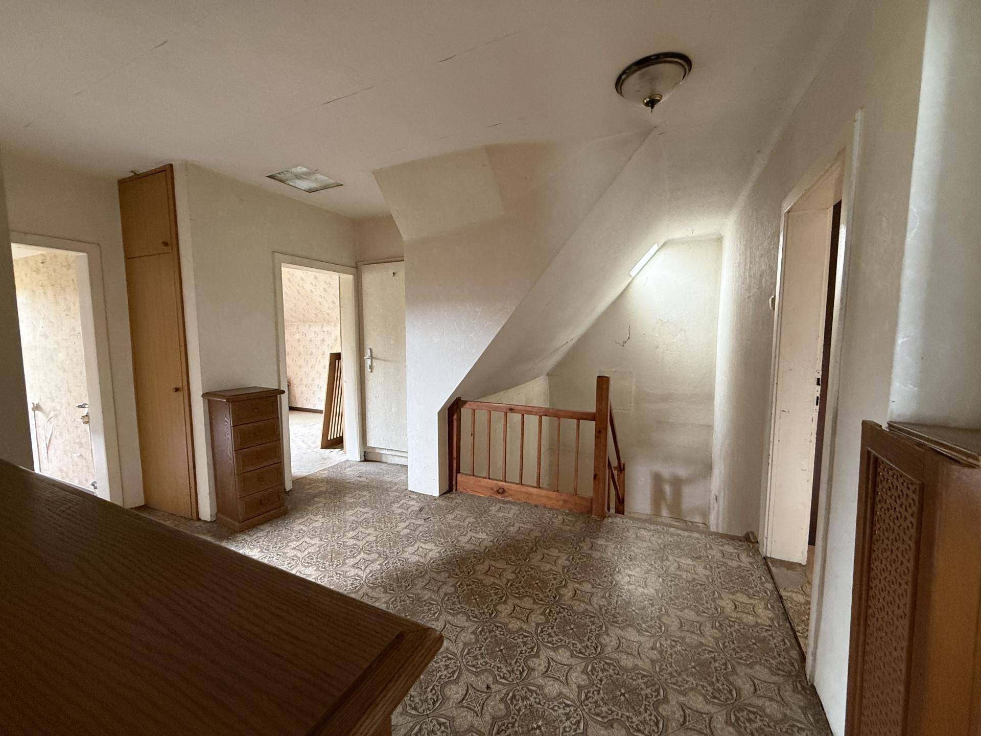 Ein Flur im Dachgeschoss mit gemustertem Vinylboden, Holztreppe und Zugang zu mehreren Räumen.
