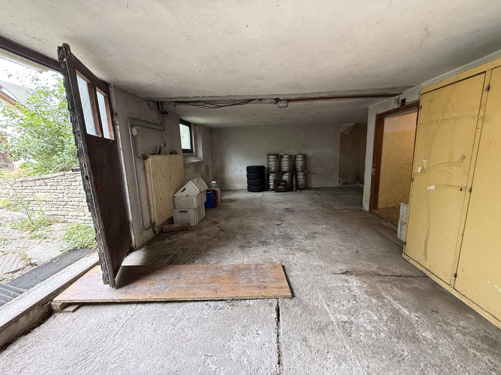 Geräumige Garage mit Betonboden und Zugang zum Außenbereich, ideal für Fahrzeuge und Lagerung.