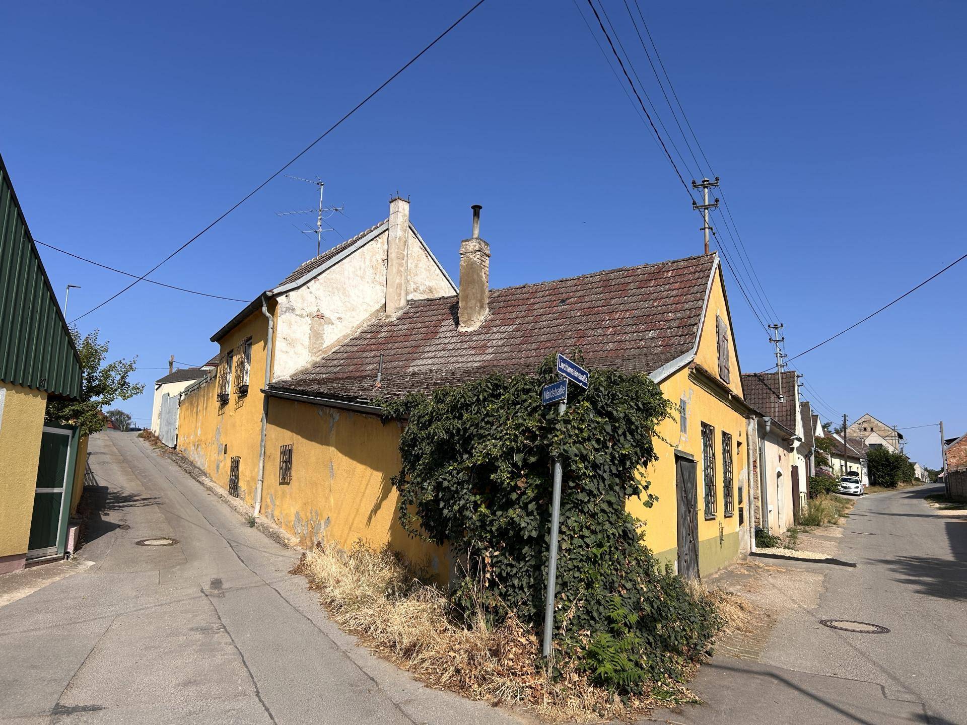 Historisches gelbes Haus an einer Straßenecke mit Blick auf die ländliche Umgebung.