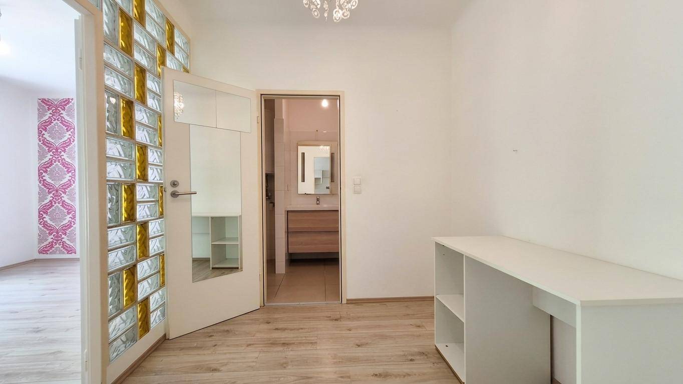 Heller Flur mit Holzboden, Glasbausteinwand und Zugang zu weiteren Räumen.