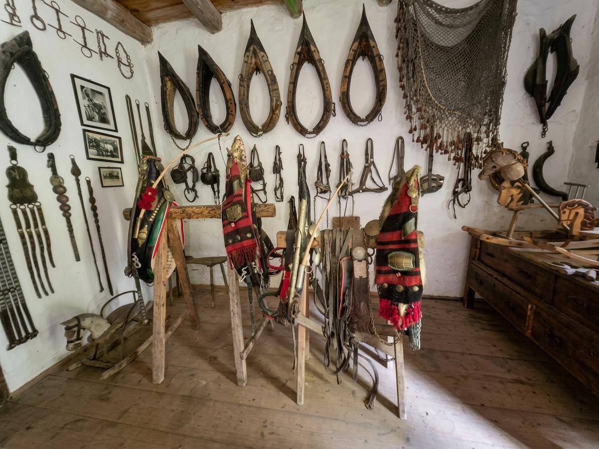 Raum mit einer Sammlung traditioneller Pferdegeschirre und Reitausrüstung an der Wand.