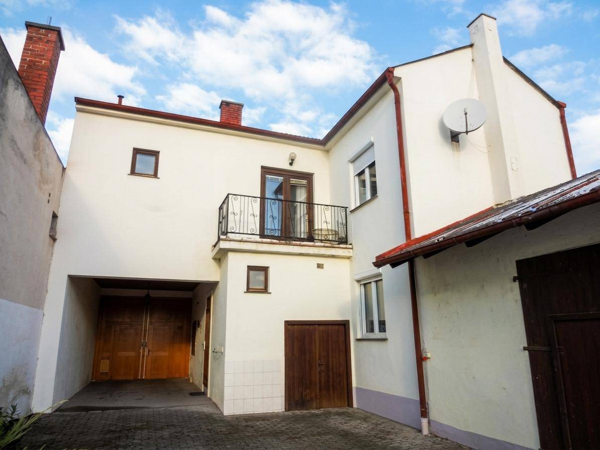 Rückansicht des Hauses mit kleinem Balkon und Garagentor im Erdgeschoss.