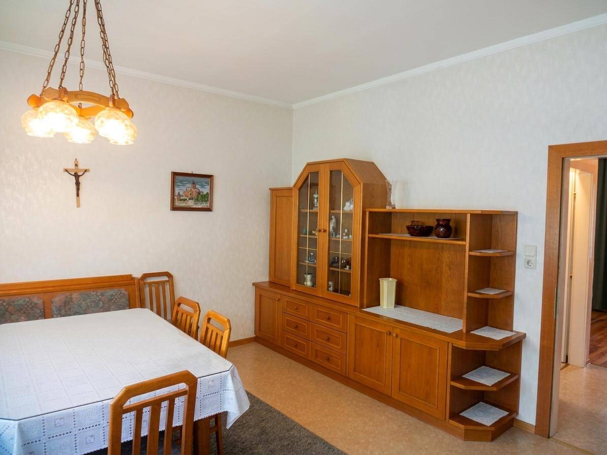 Gemütlicher Essbereich mit Holztisch, Stühlen und einem großen Holzschrank.