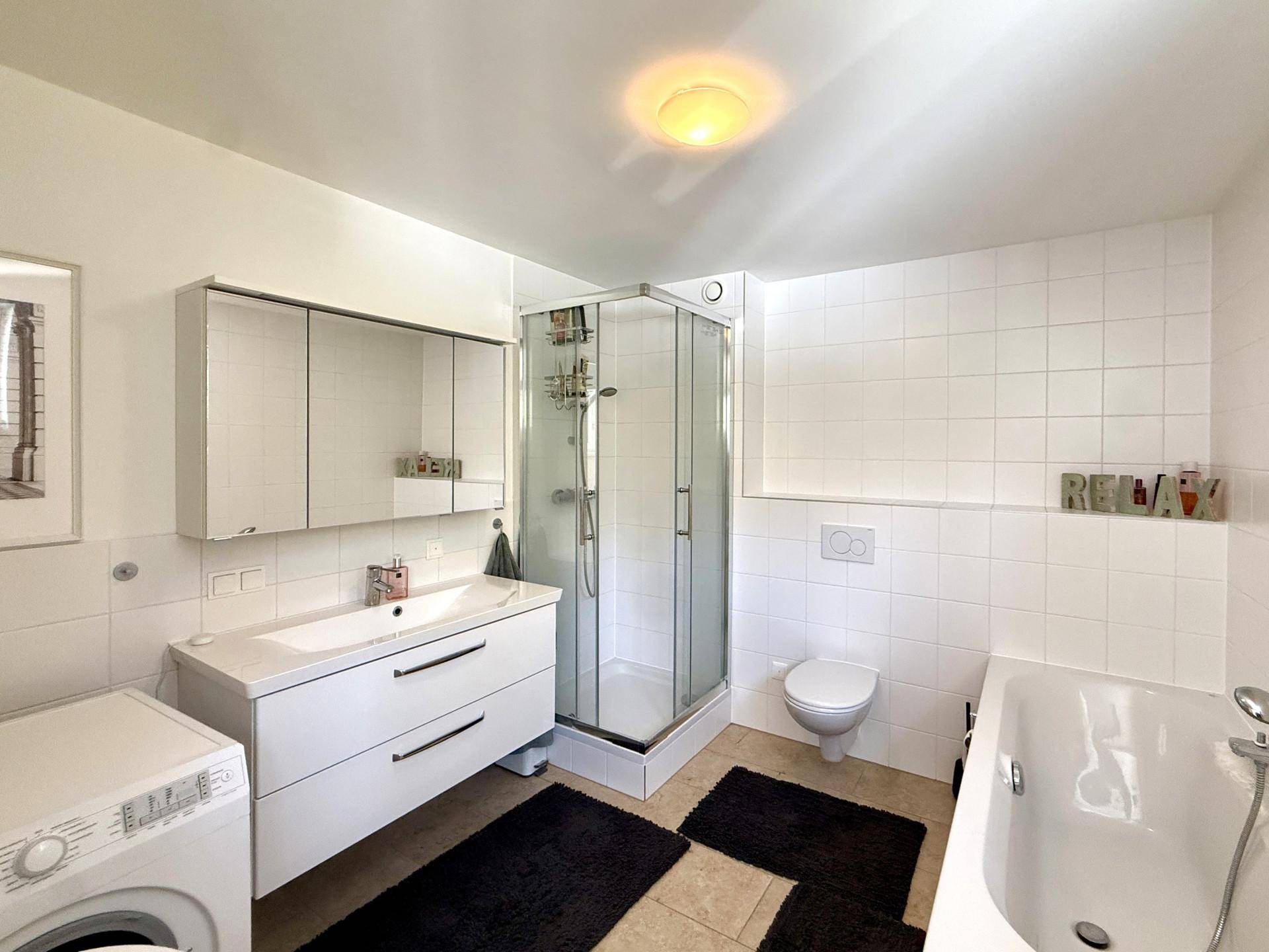 Geräumiges Badezimmer mit Dusche, Badewanne, Waschbecken und Waschmaschine.