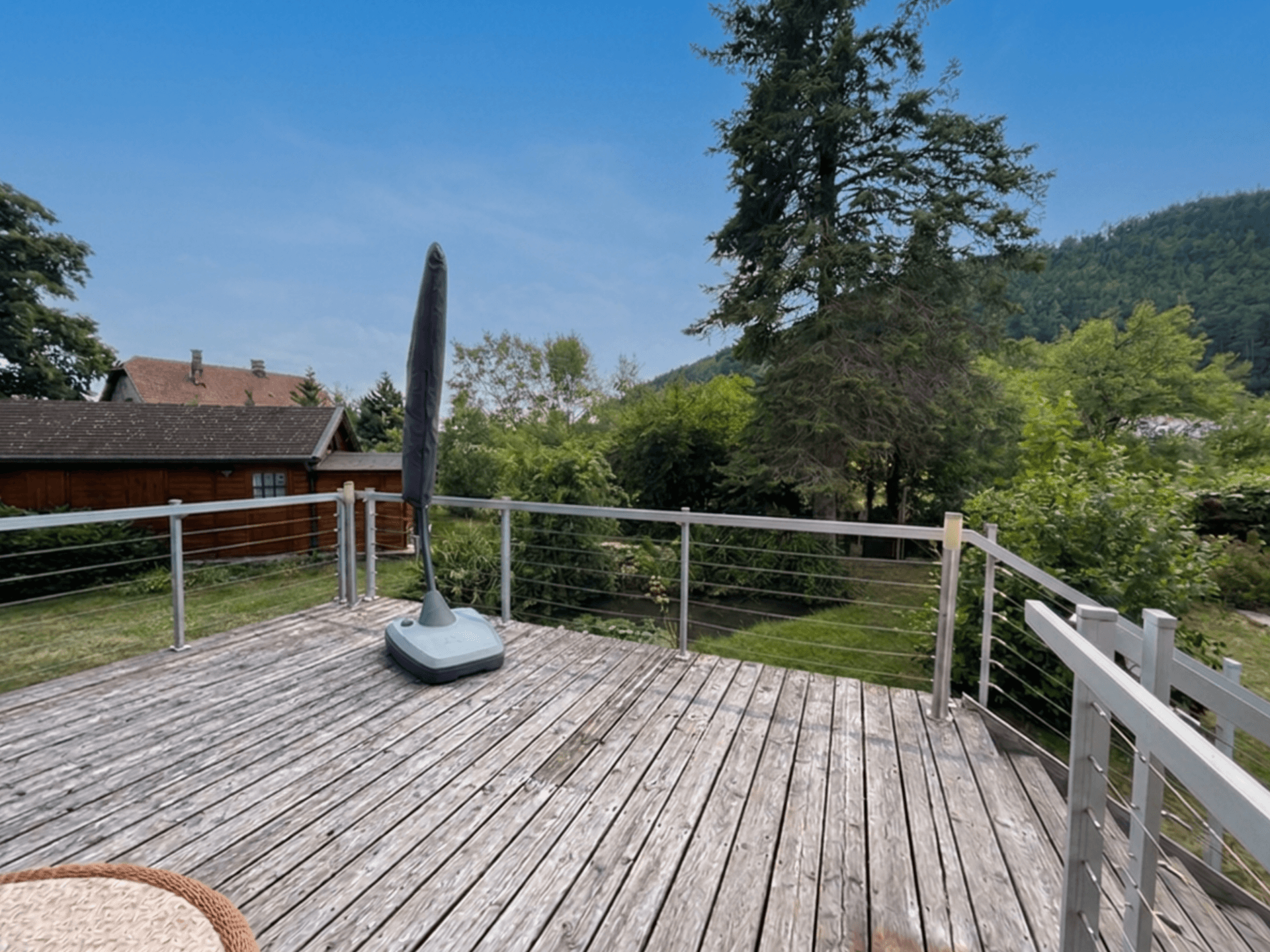 Geräumige Holzterrasse mit Geländer und weitem Blick in die Natur.