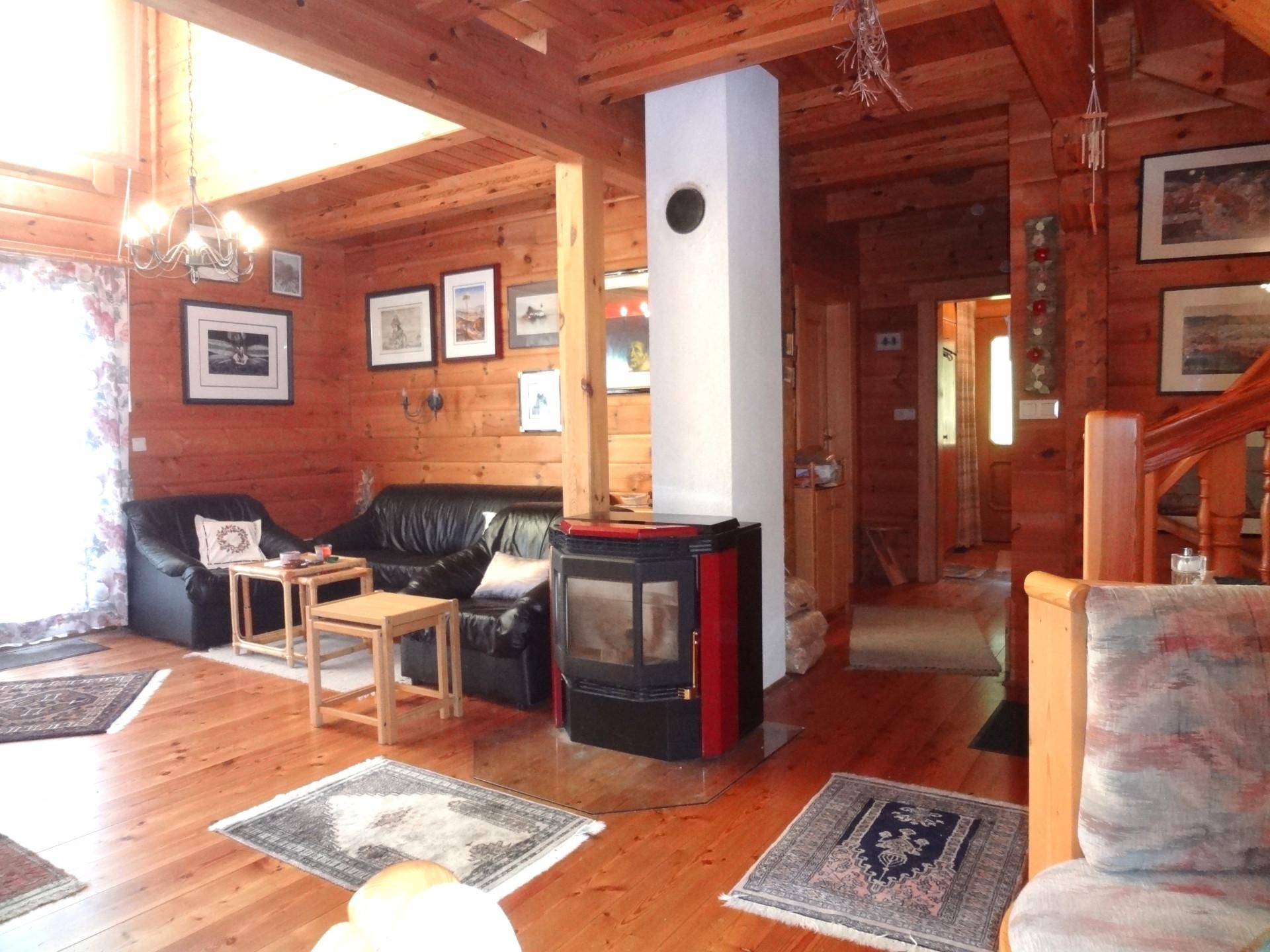 Rustikales Wohnzimmer mit Holzbalken, Kaminofen und bequemen Ledersofas.