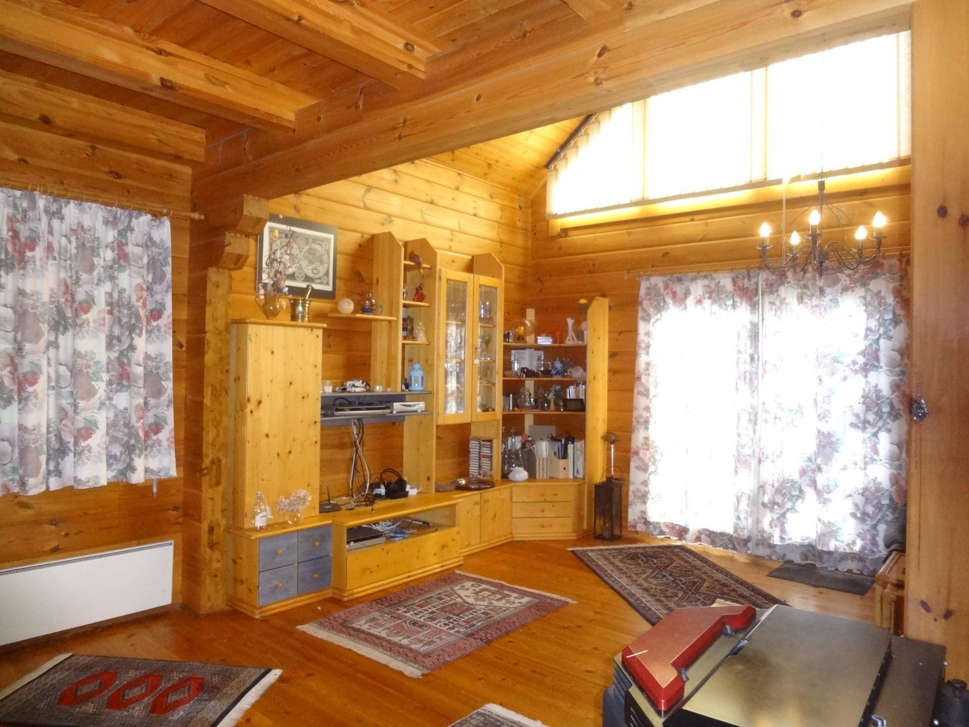 Helles Wohnzimmer mit Holzvertäfelung, großen Fenstern und rustikalen Möbeln.