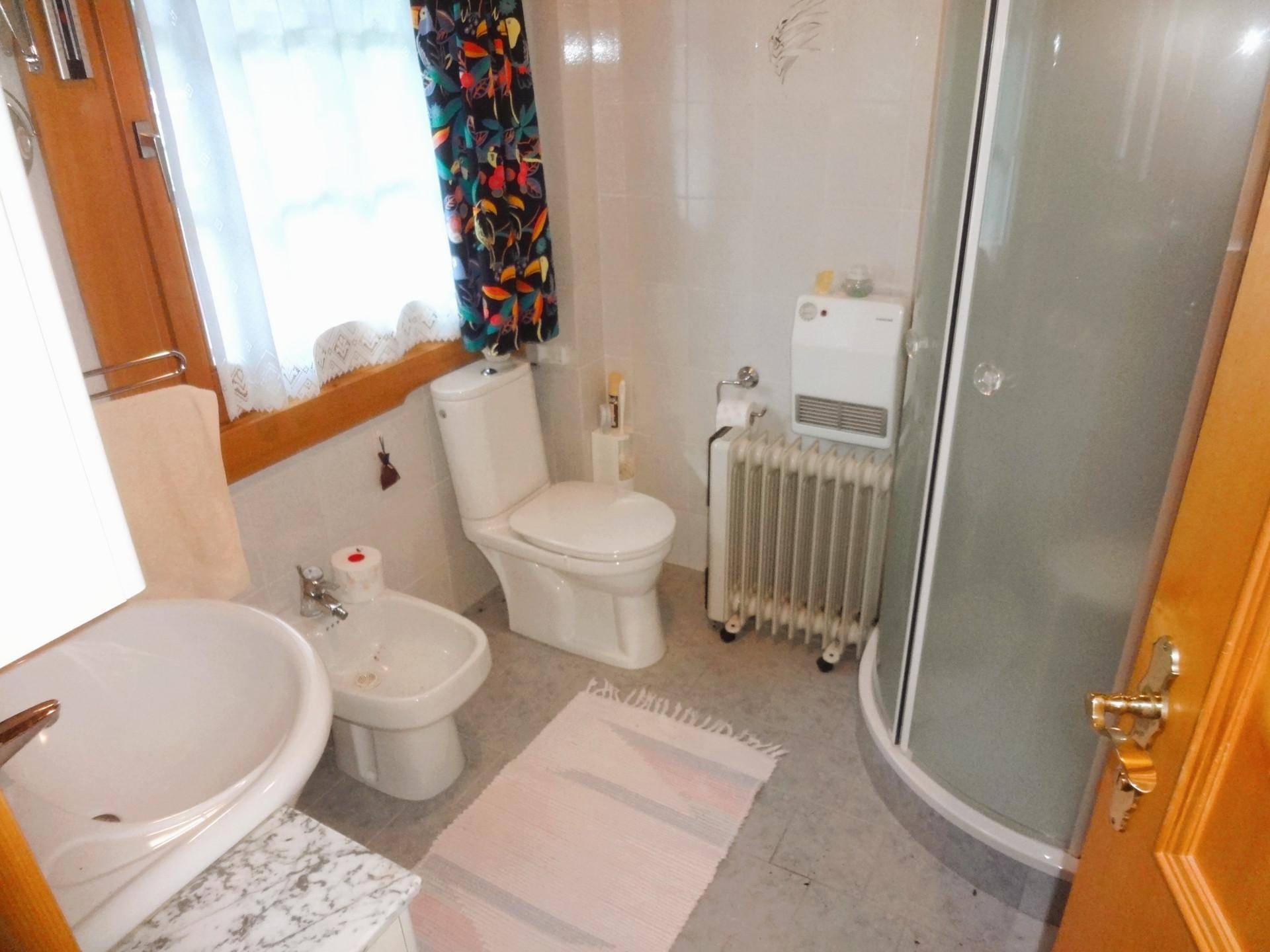 Helles Badezimmer mit Dusche, Bidet, WC und Fenster.