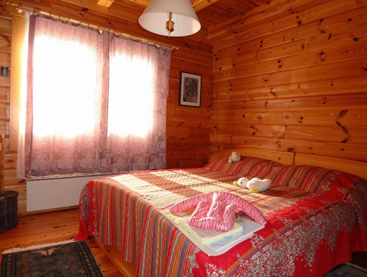 Gemütliches Schlafzimmer mit Holzwänden, Doppelbett und viel natürlichem Licht.