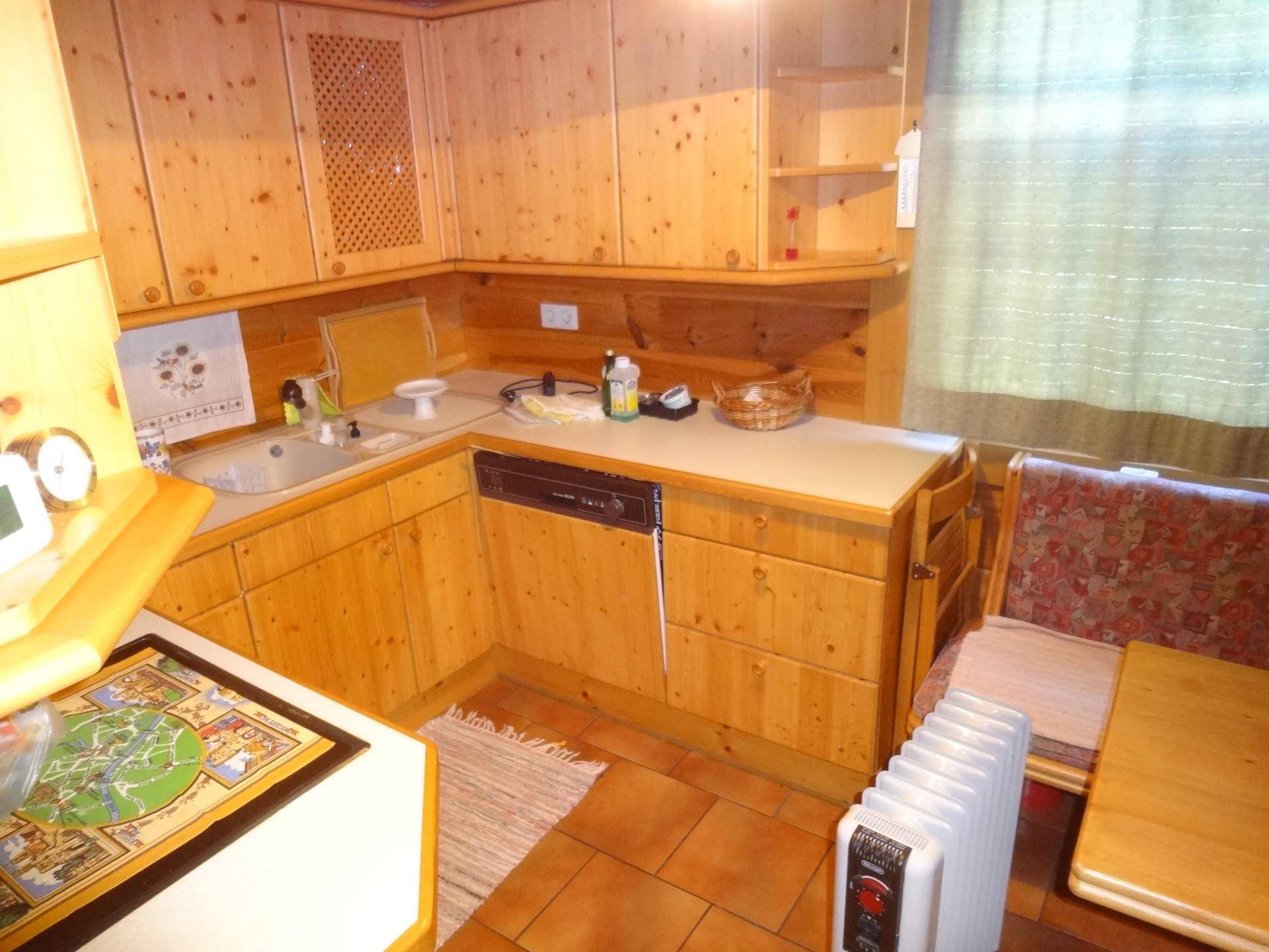 Funktionale Holzküche mit Einbauschränken, Spülmaschine und Essbereich.