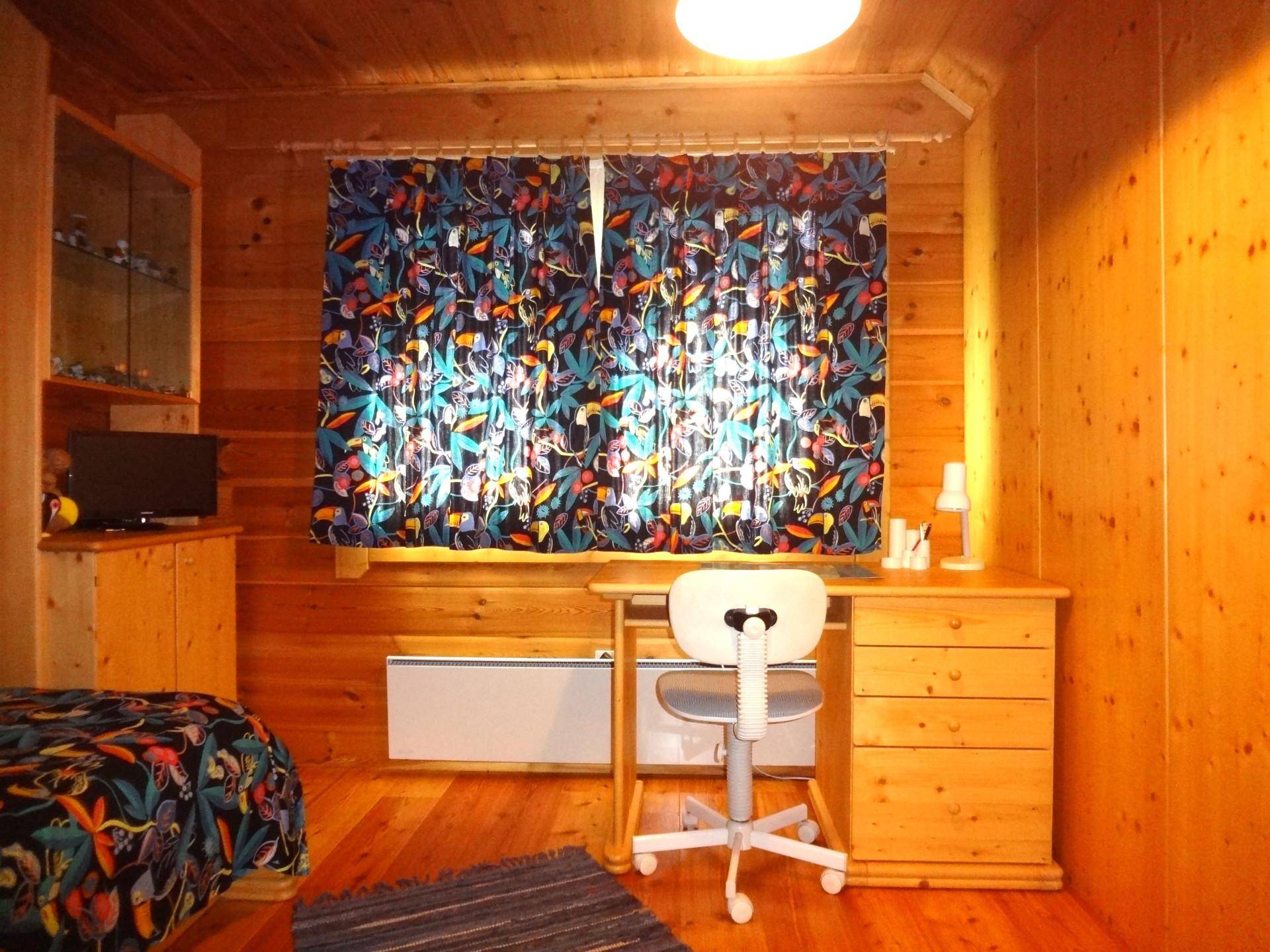 Arbeitszimmer mit Holzwänden, Schreibtisch und farbenfrohen Vorhängen.