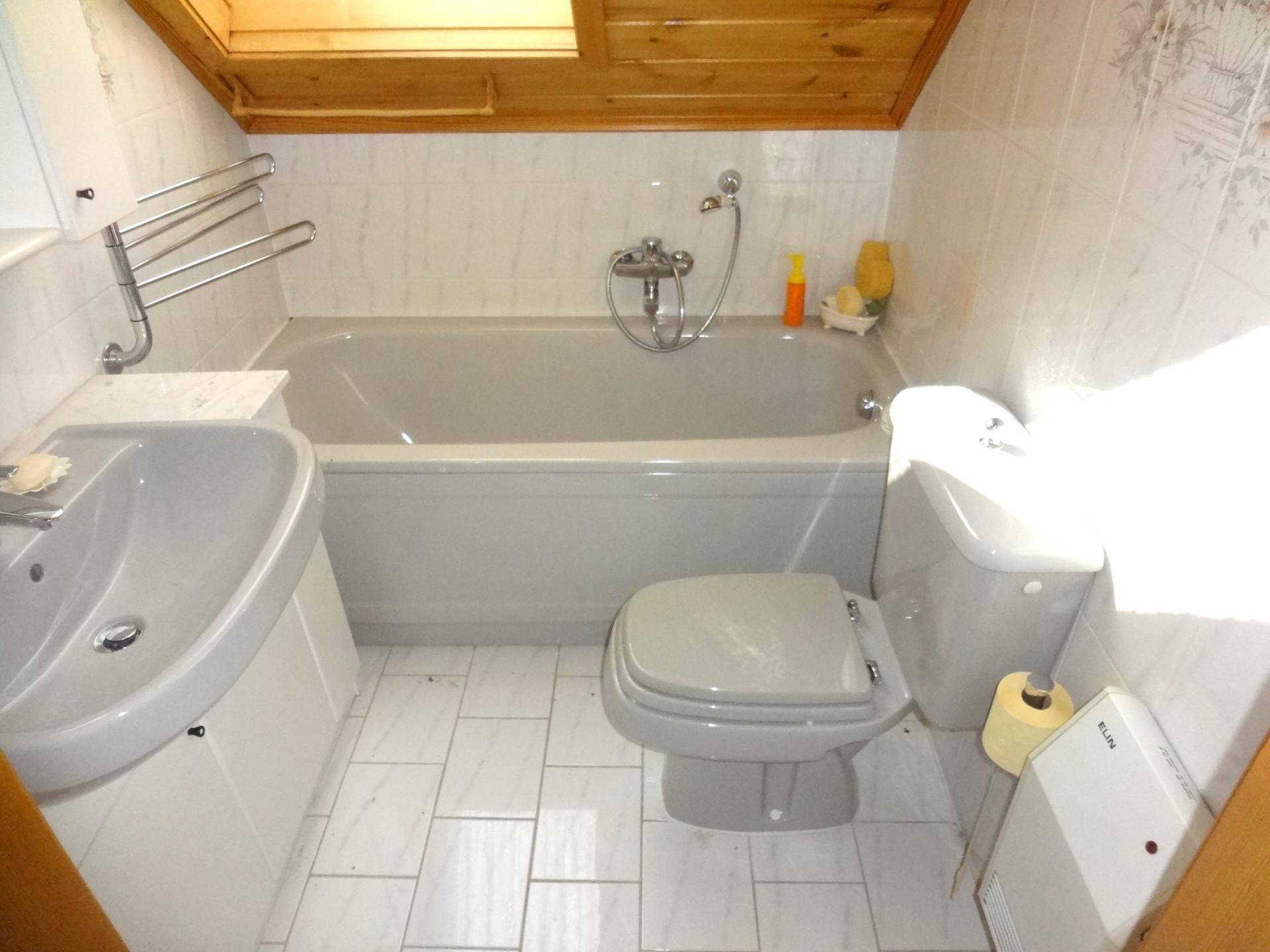 Badezimmer im Dachgeschoss mit Badewanne, WC, Waschbecken und Dachfenster.