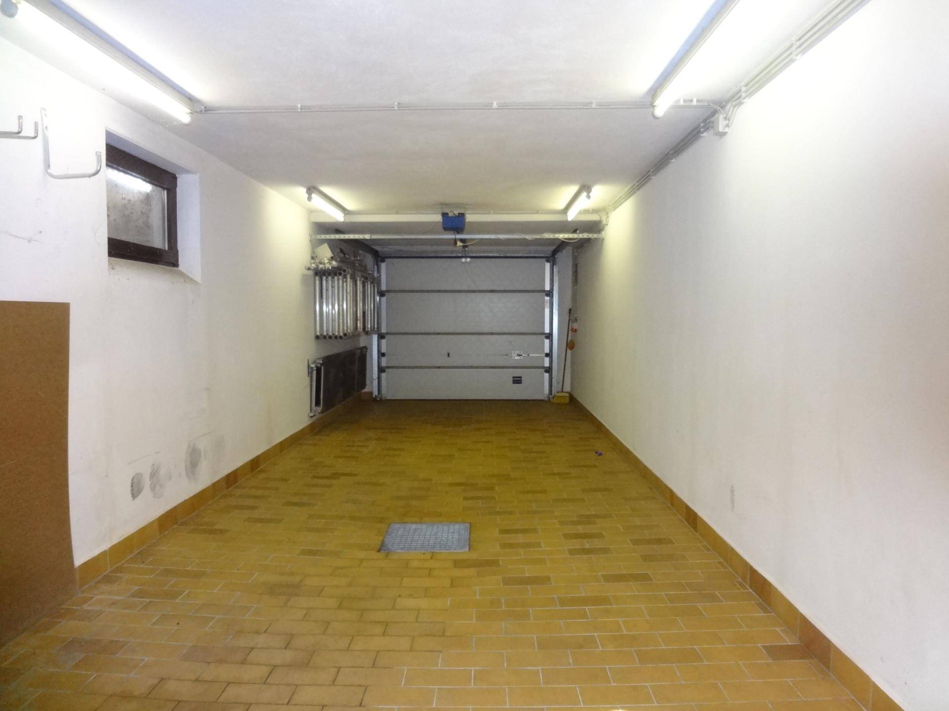 Geräumige Garage mit Fliesenboden und automatischem Garagentor.