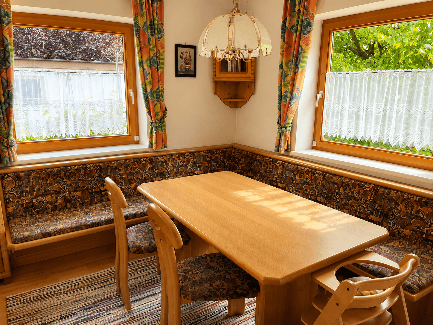 Gemütlicher Essbereich mit Eckbank, Holztisch und traditionellen Vorhängen, ideal für Familienmahlzeiten.