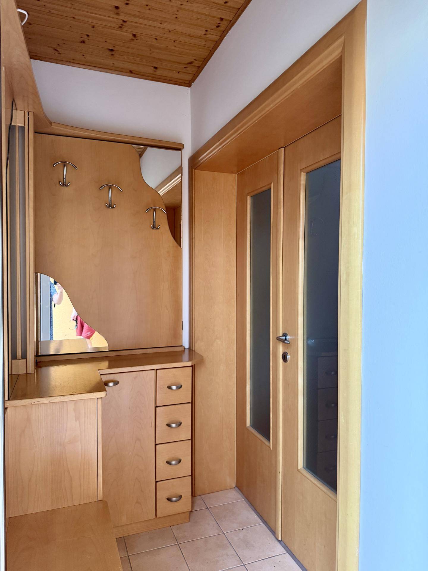 Eingangsbereich mit maßgefertigten Holzmöbeln, Spiegel und Fliesenboden, bietet praktischen Stauraum.