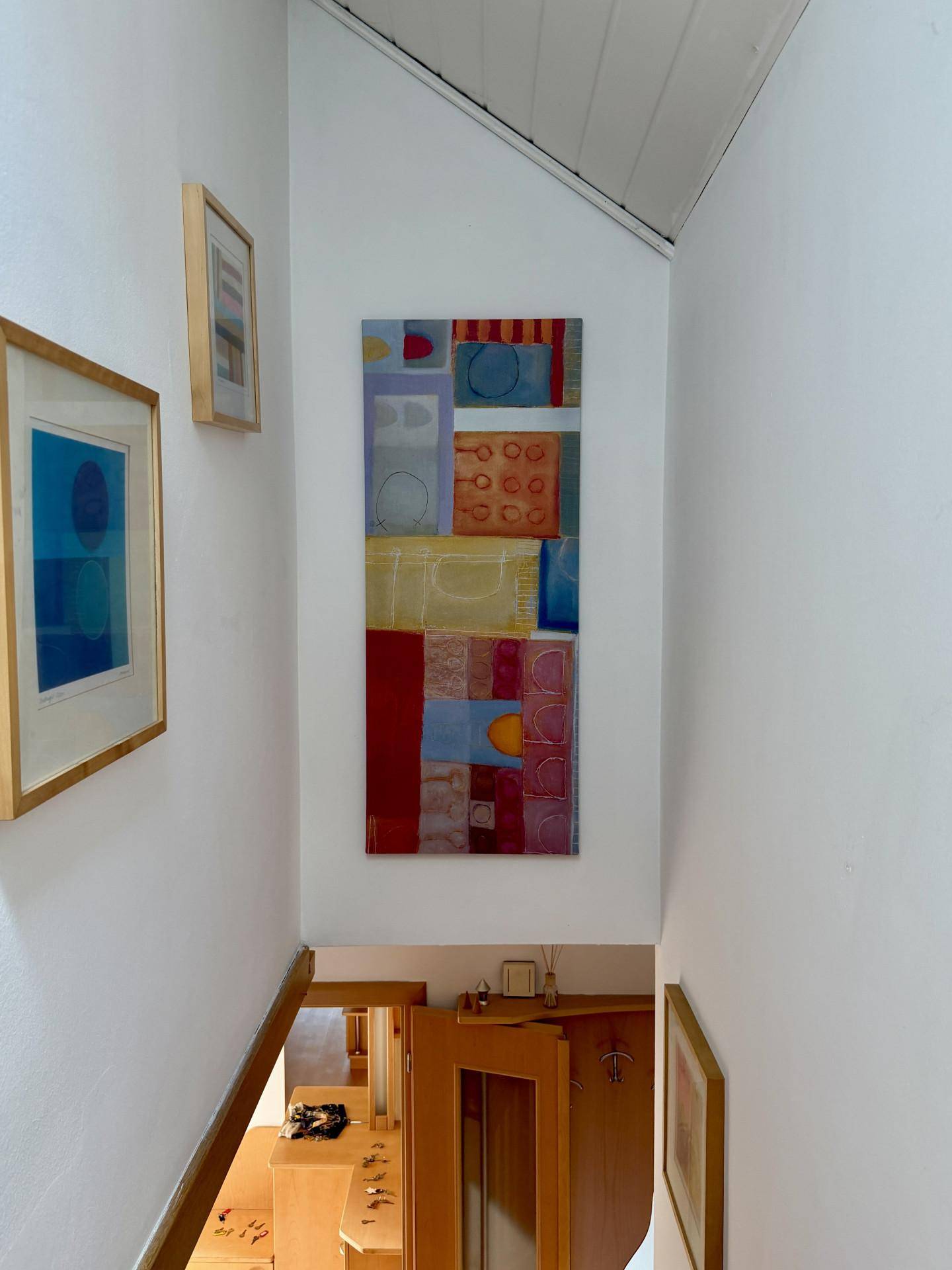 Heller Treppenaufgang mit weiß gestrichenen Wänden, Holzdecke und moderner Kunstdekoration.