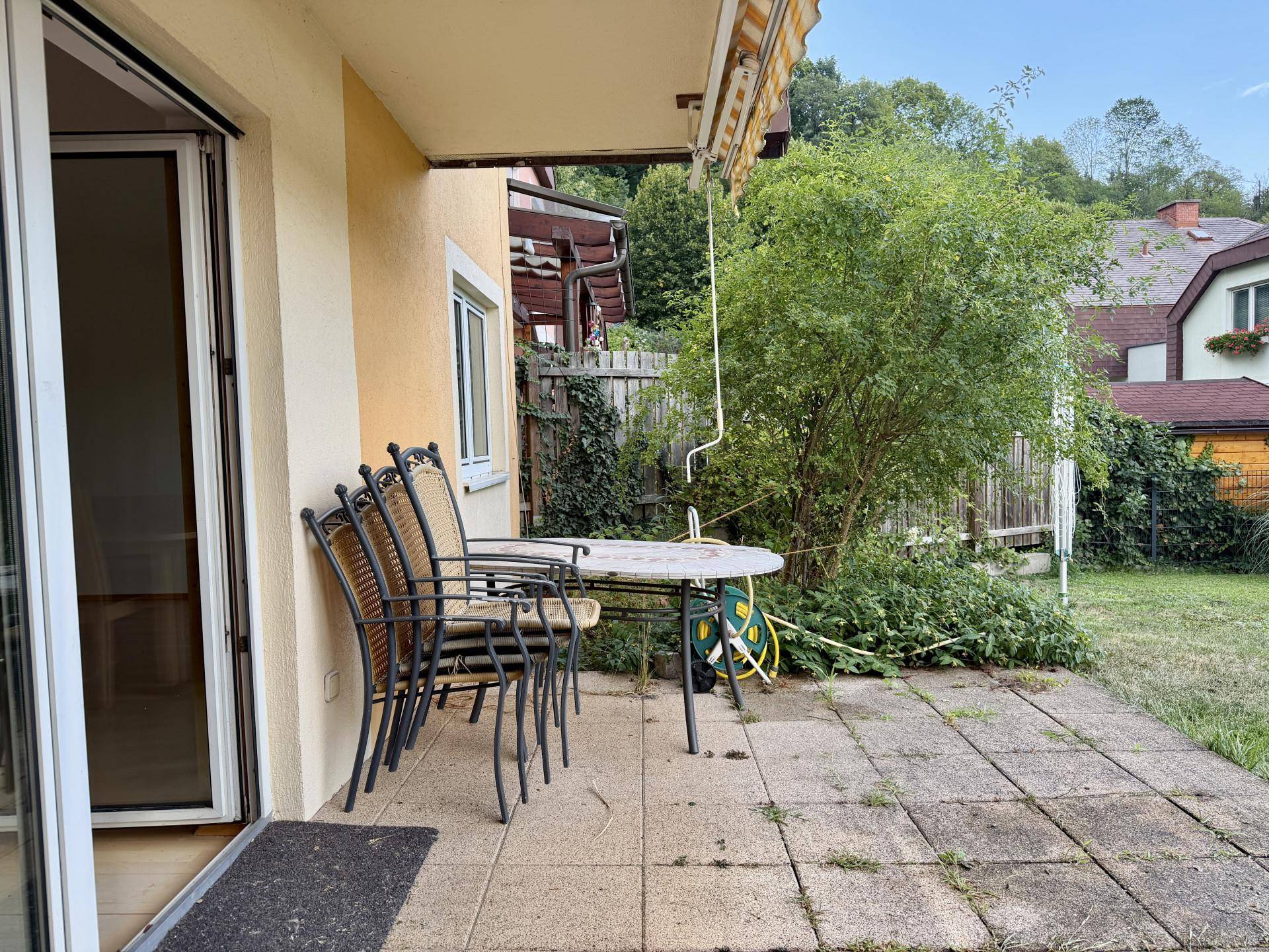Geräumige Terrasse mit Sitzgelegenheiten und direktem Zugang zum grünen Gartenbereich.