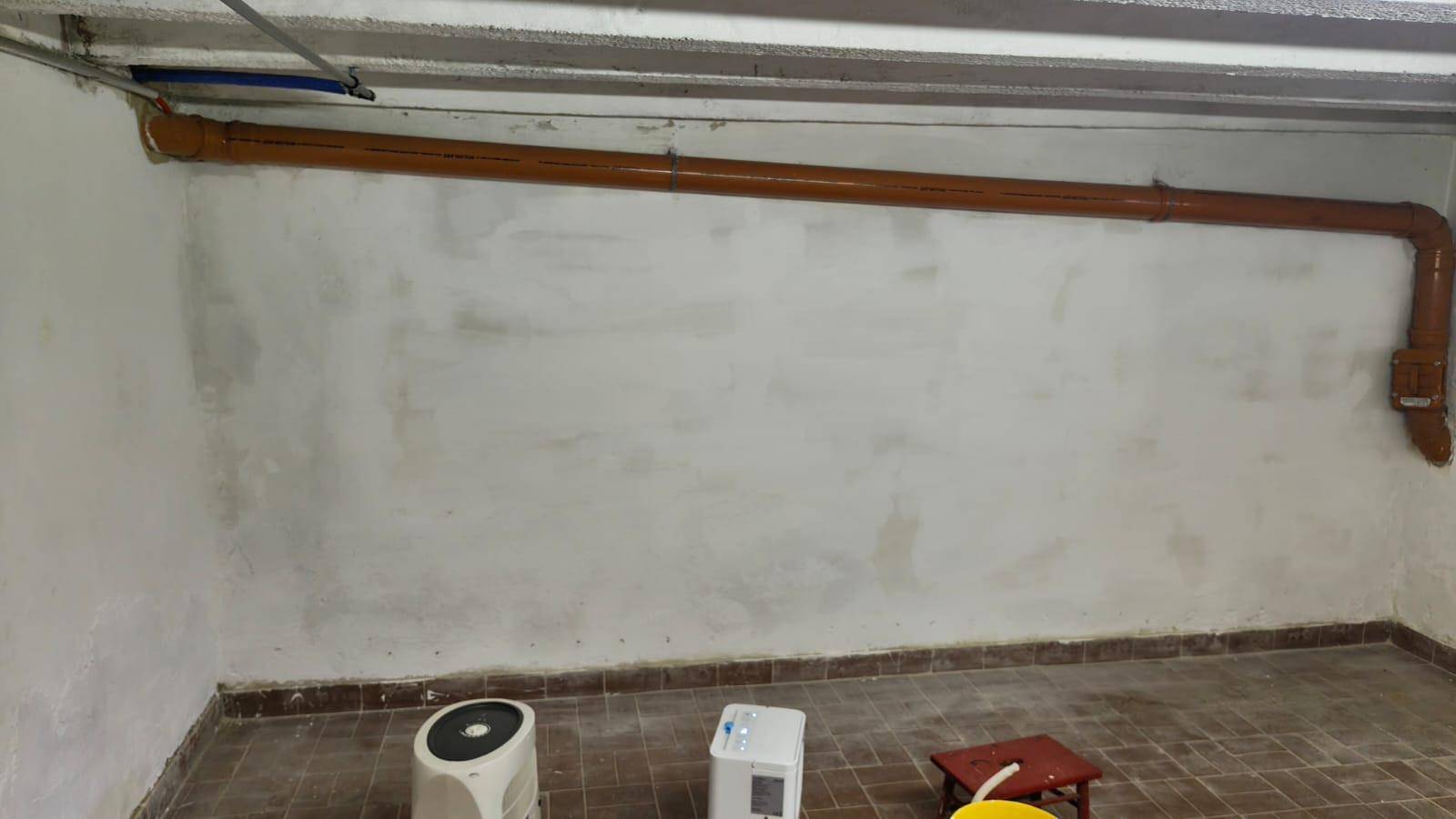 Unfertiger Kellerraum mit sichtbaren Rohren und Fliesenboden, bereit für zukünftigen Ausbau.