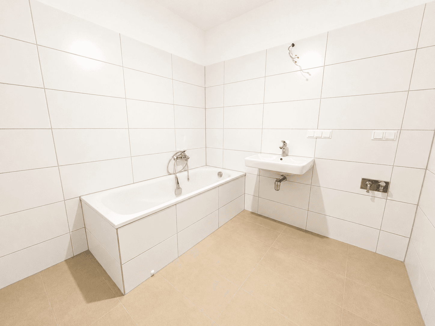 Modernes Badezimmer mit weißen Fliesen, einer Badewanne und einem einzelnen Waschbecken.