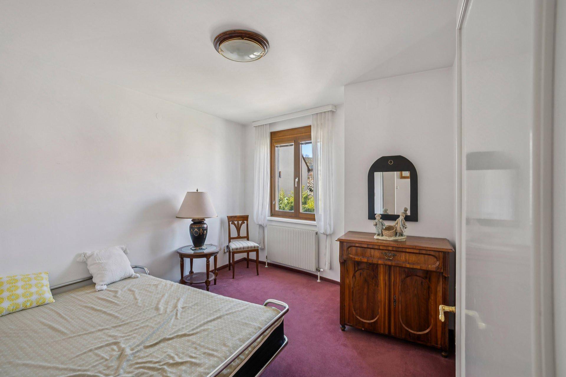 Schlafzimmer mit rosa Teppichboden, traditionellen Holzmöbeln und einem Fenster.