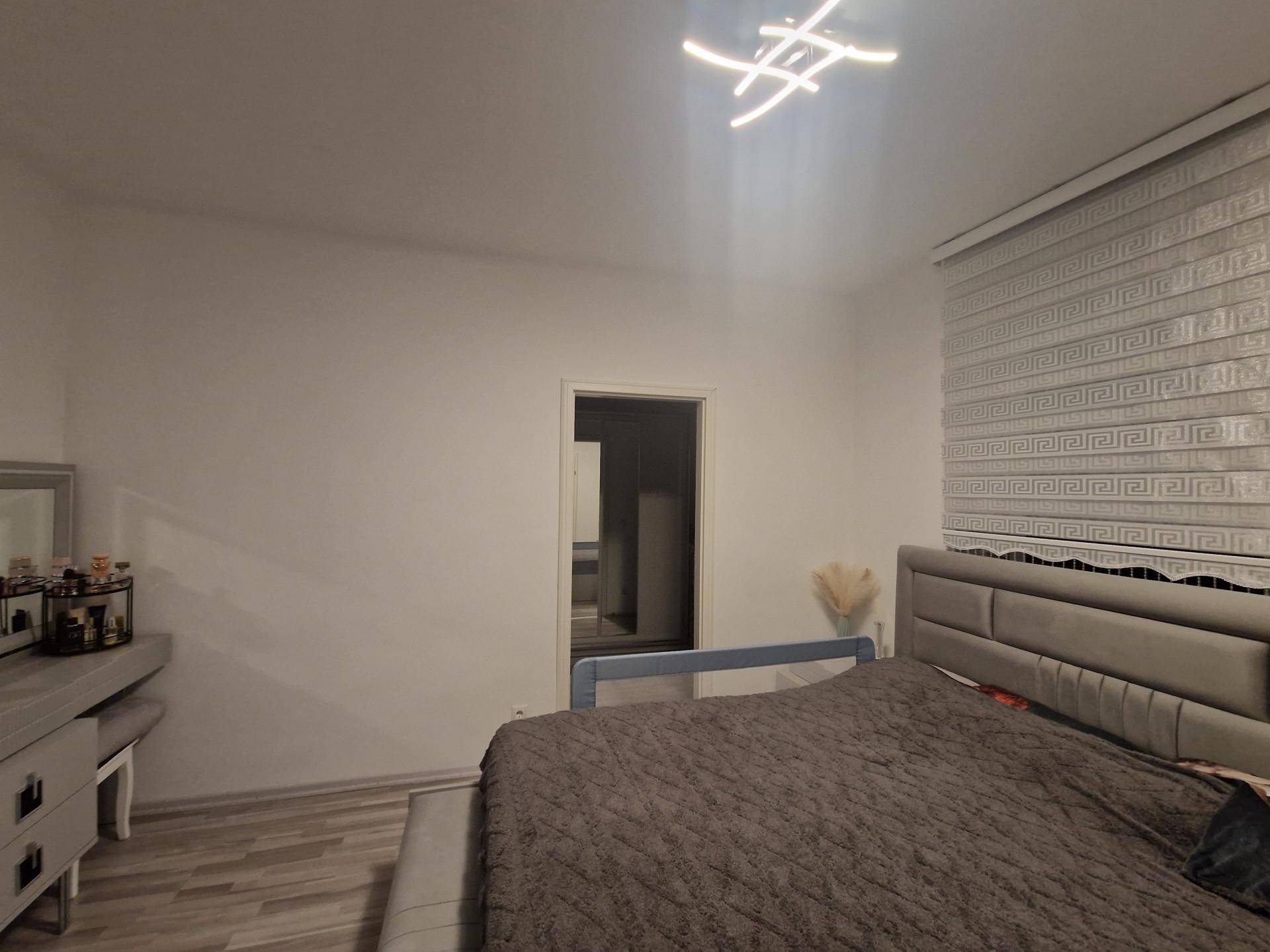 Gemütliches Schlafzimmer mit großem Bett, modernem Rollo und schlichter Einrichtung.