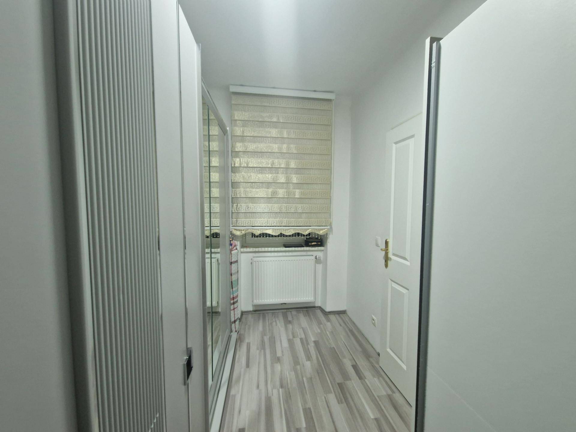 Heller Flur mit Spiegelschrank, Fenster und Heizkörper, der zu weiteren Räumen führt.
