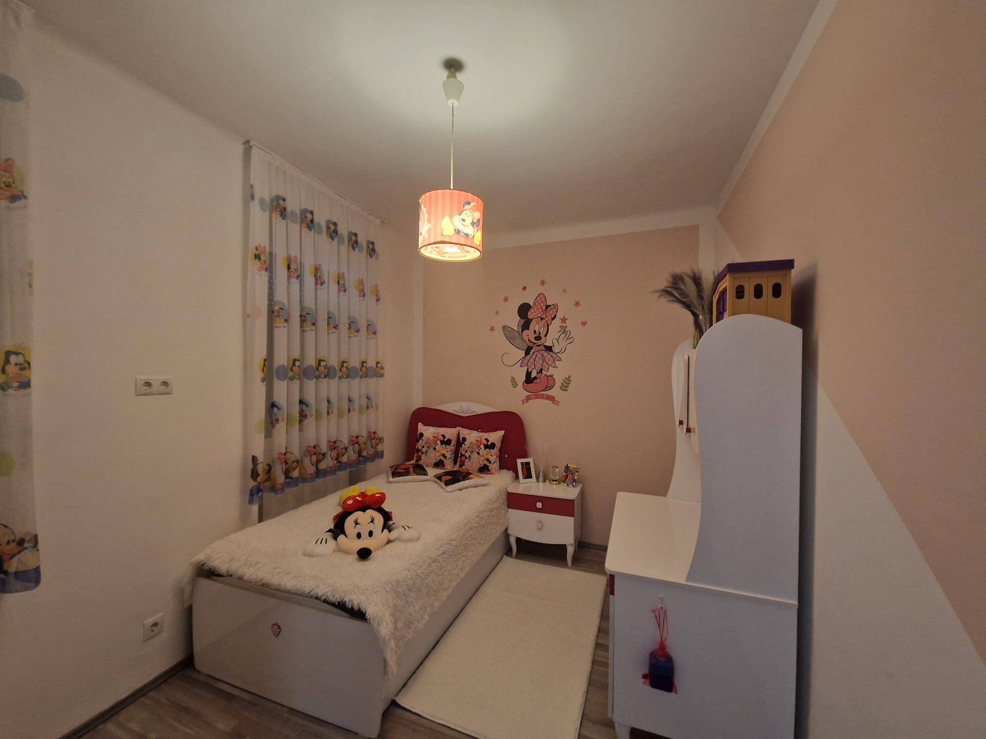 Kinderzimmer mit Einzelbett, Minnie-Maus-Dekoration und farbenfrohen Vorhängen.