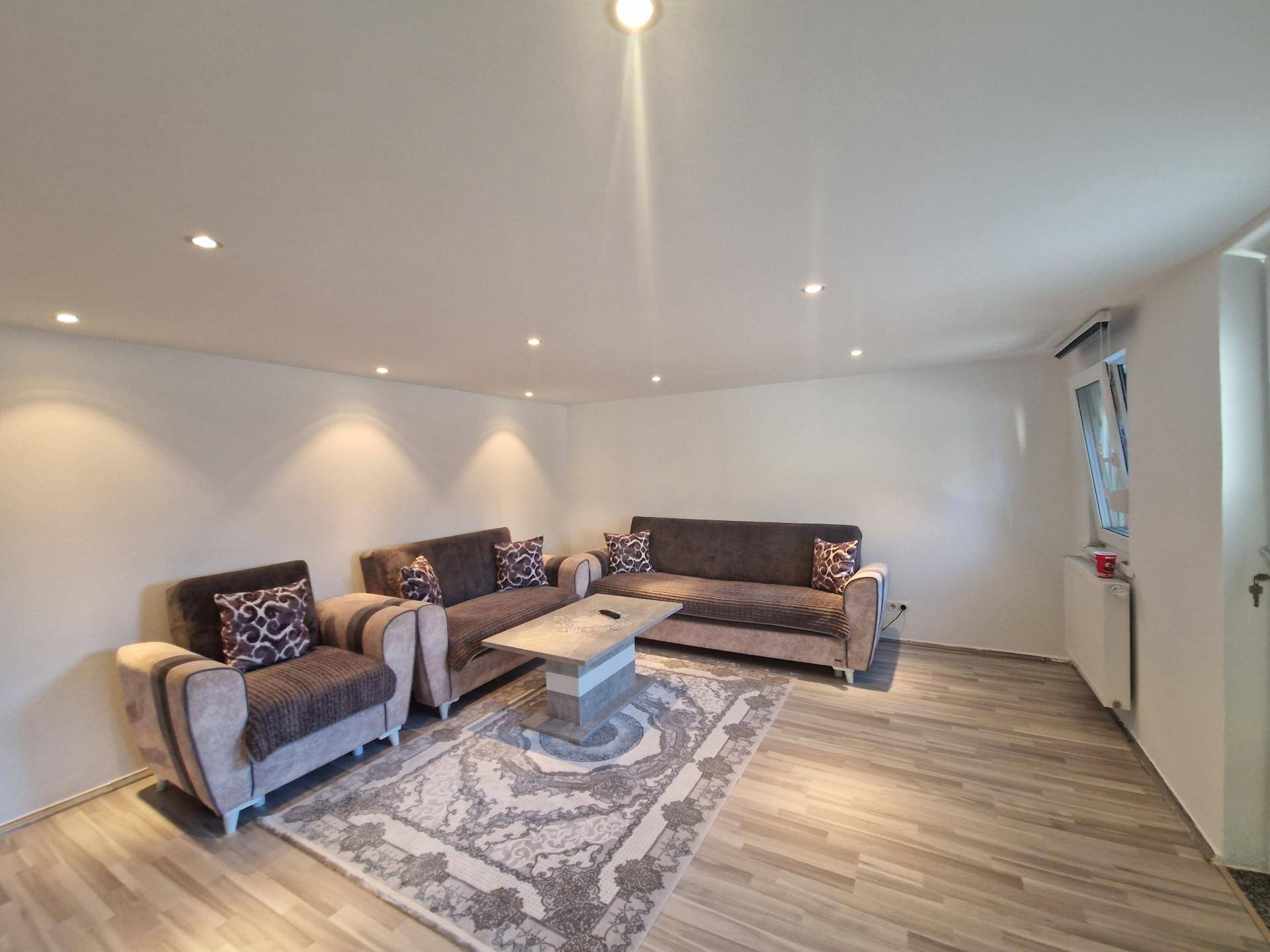 Geräumiges Wohnzimmer mit bequemen Sofas, Teppich und indirekter Beleuchtung.
