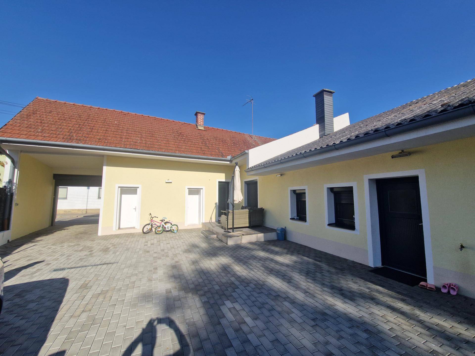 Gepflasterter Innenhof mit Zugang zu mehreren Gebäudeteilen und einem Garagenbereich.