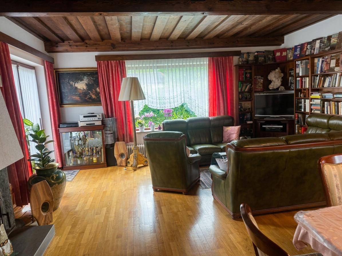 Gemütliches Wohnzimmer mit Holzbalkendecke, Ledersofas und Bücherregalen, hell und einladend.